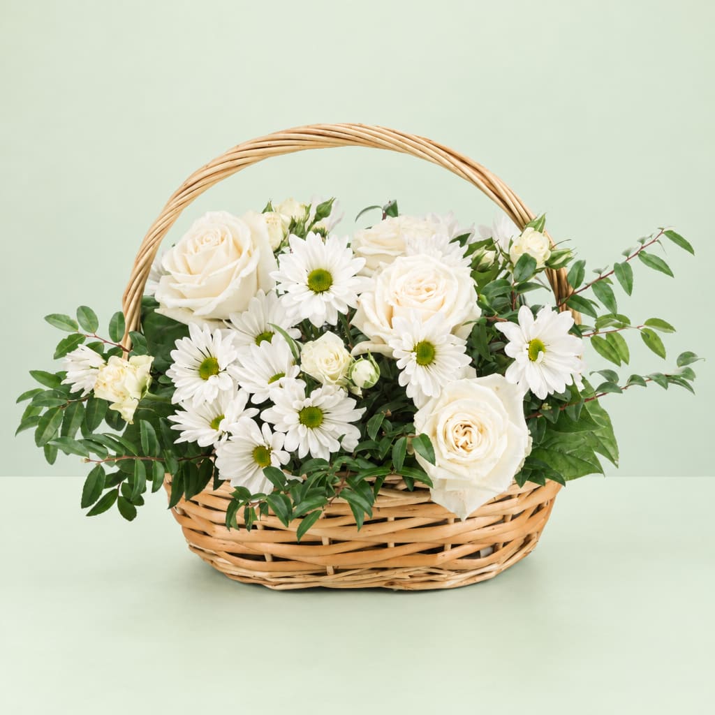 White roses and daisies arranged in a wicker basket