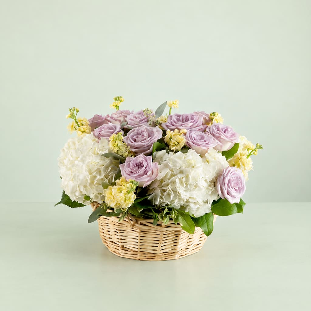 Lavender roses and white hydrangeas in a wicker basket