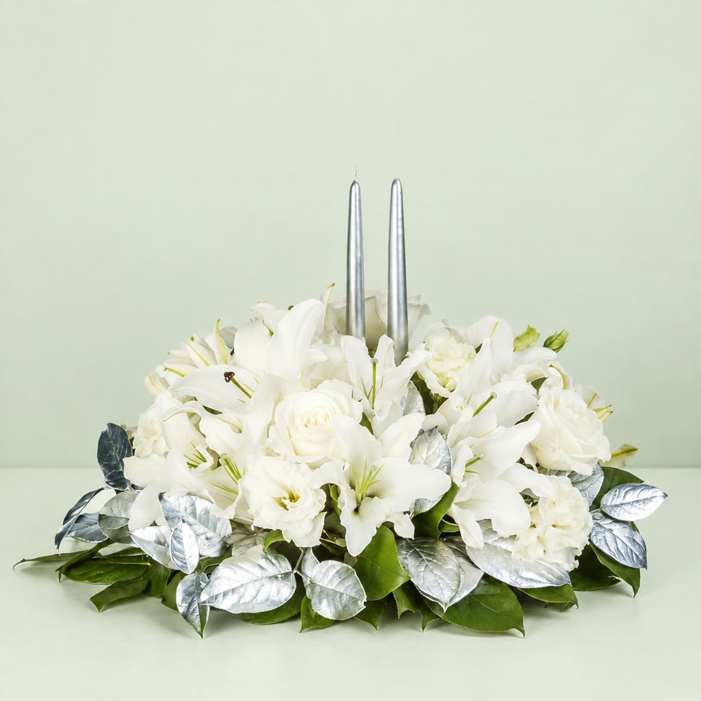 White floral centerpiece with two silver taper candles