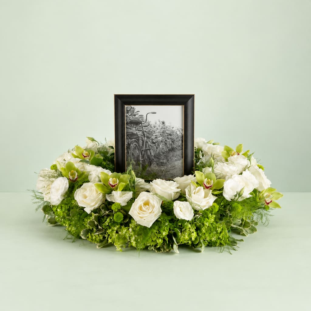 White rose and orchid wreath around a framed black-and-white photo
