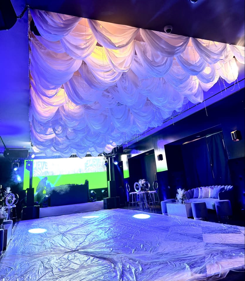 Event venue with draped white ceiling fabric and blue lighting