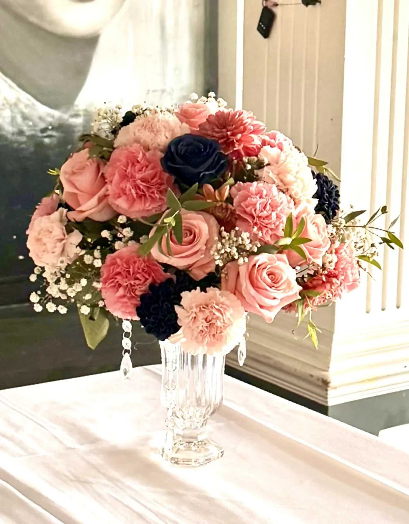 Pink and coral bouquet with roses and carnations in a clear glass vase