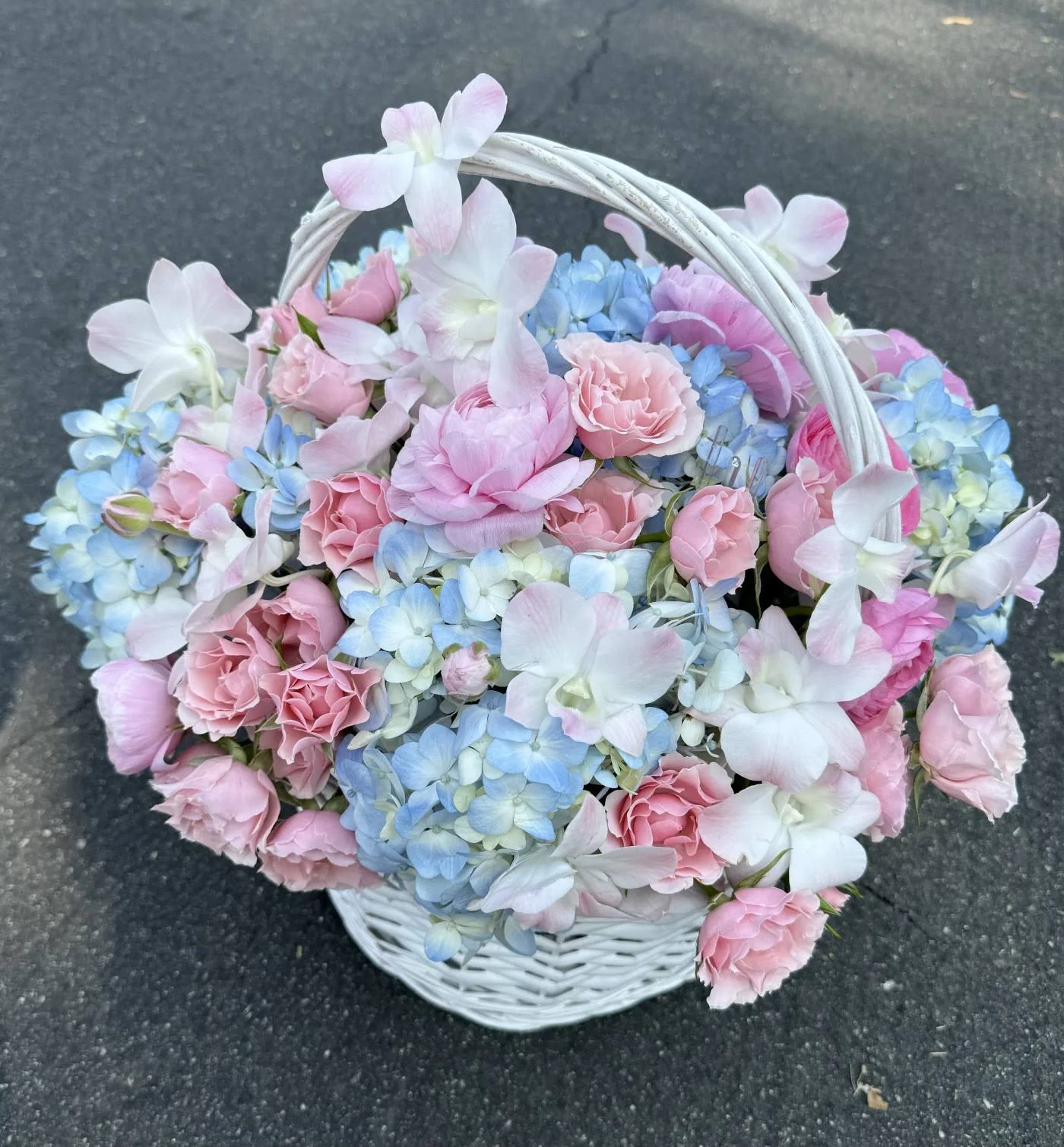 Basket of pink and blue flowers with a white handle