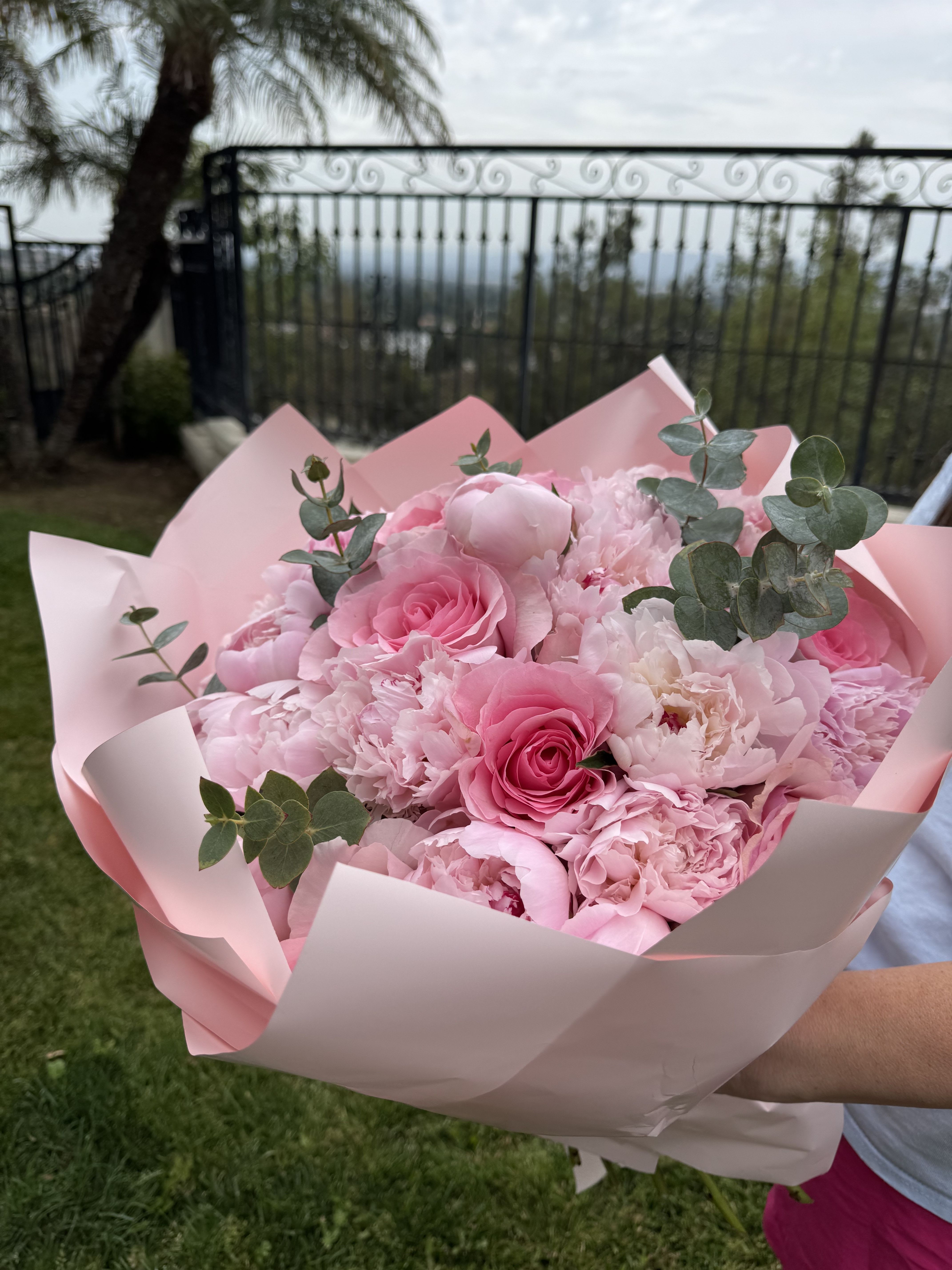 Pink bouquet of roses and peonies wrapped in pale pink paper