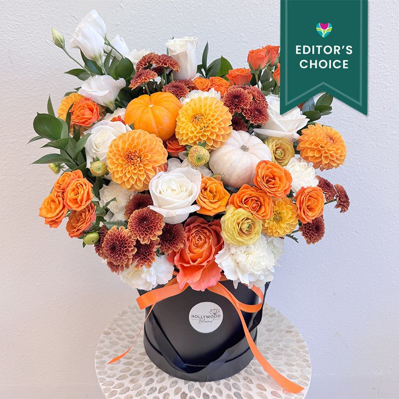 Orange and white floral arrangement in a black hatbox with a ribbon