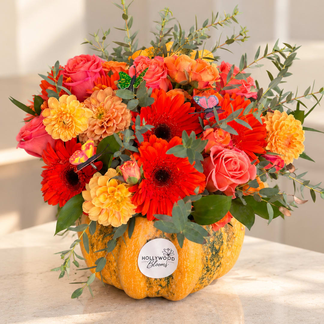 Bright mixed bouquet in a pumpkin-shaped container with pink, orange, and red blooms