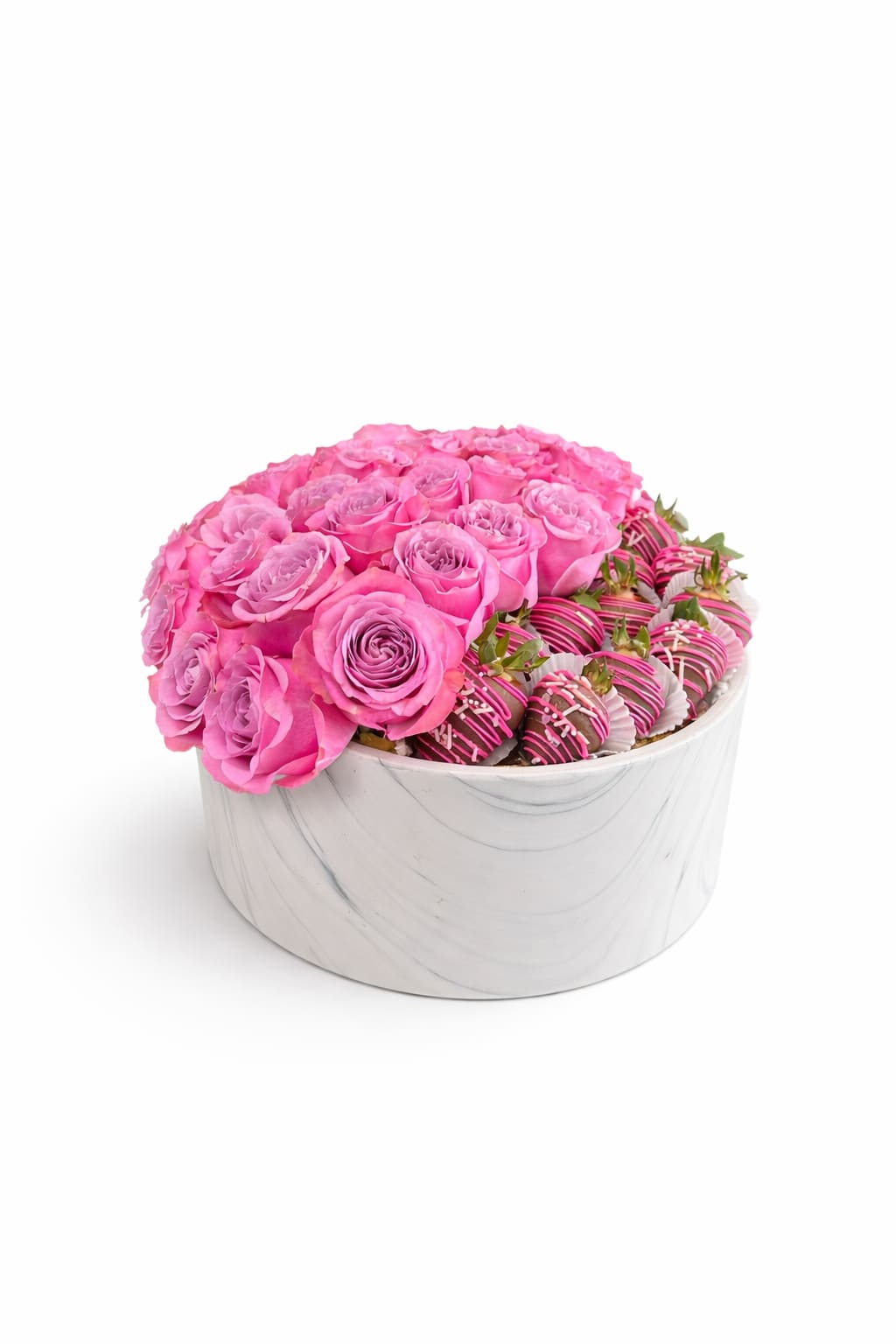 Round white box filled with pink roses and chocolate-covered strawberries drizzled with pink and white.
