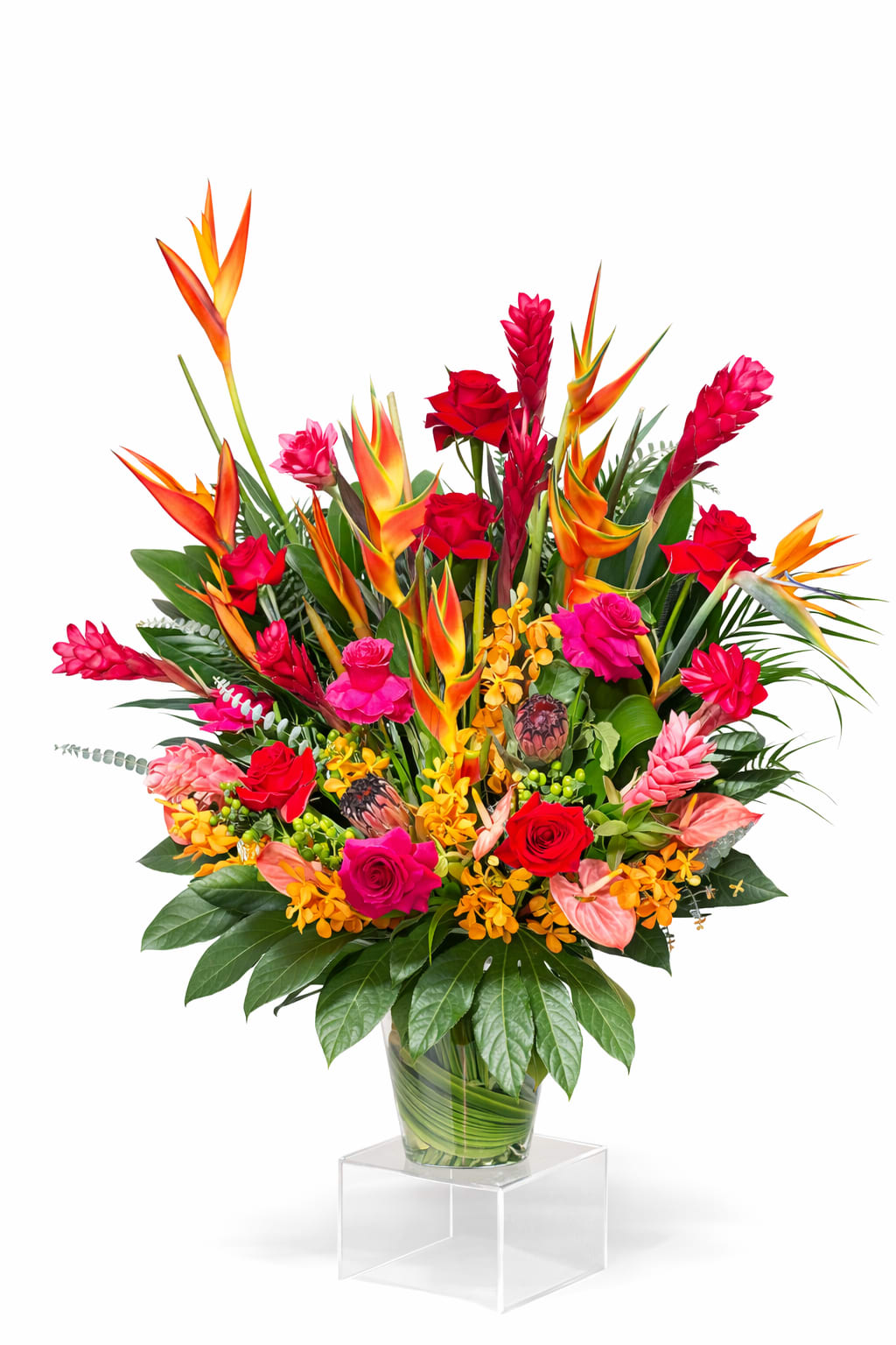 Tropical bouquet with red roses and orange bird-of-paradise in a glass vase