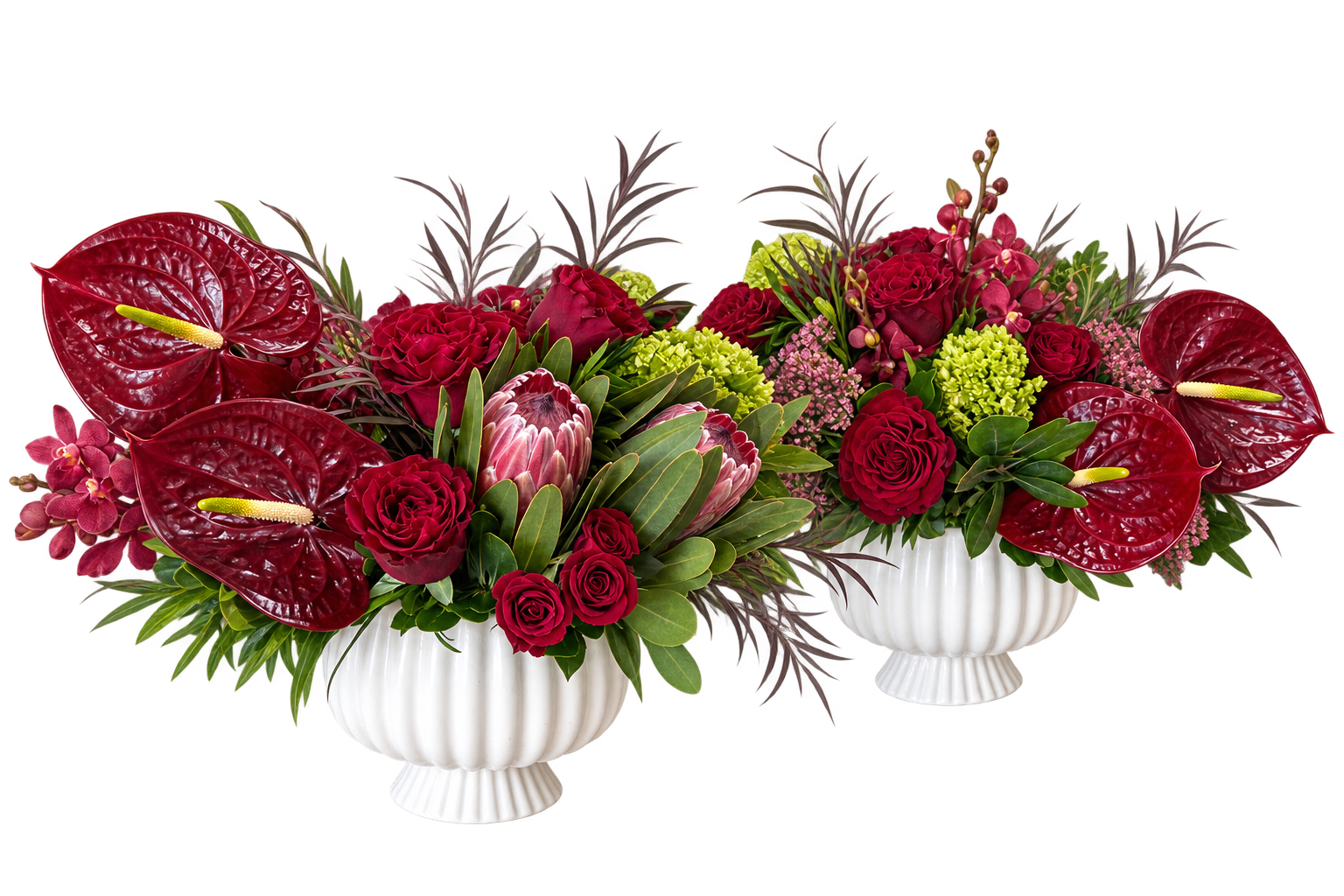 Two red floral arrangements in white urns with large anthuriums and roses