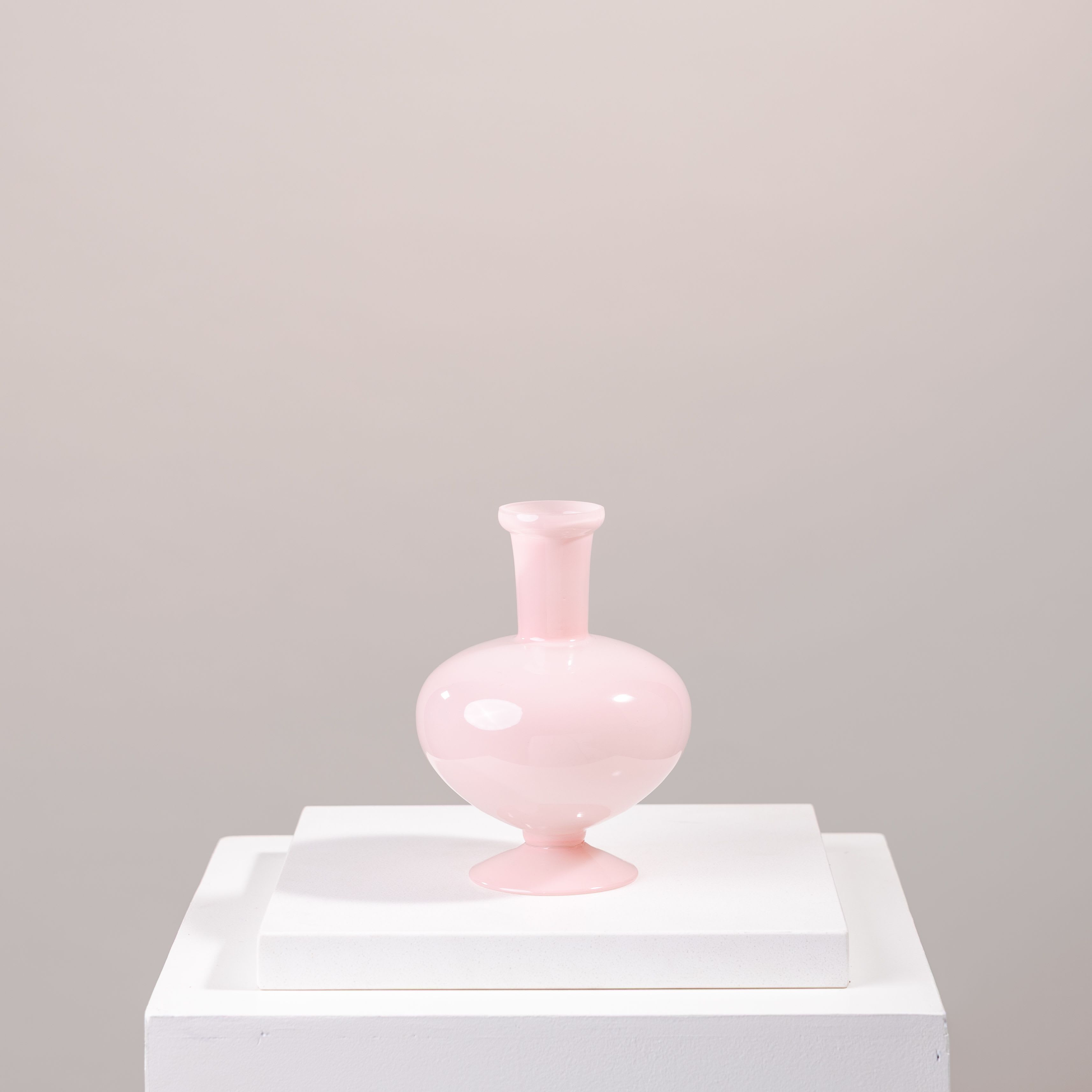 Pink glass vase on a white pedestal