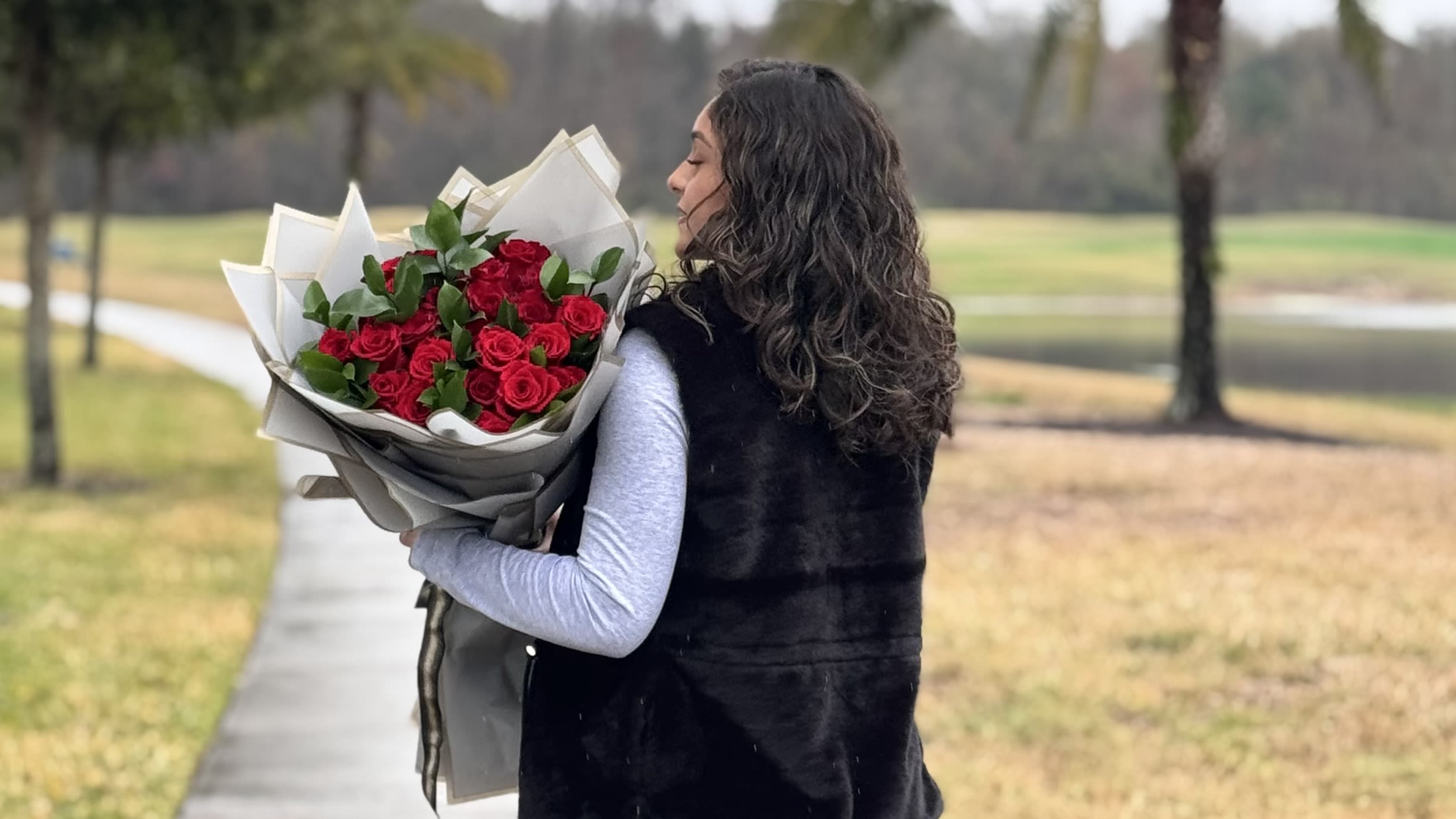 Woman holding a bouquet of red roses wrapped in paper