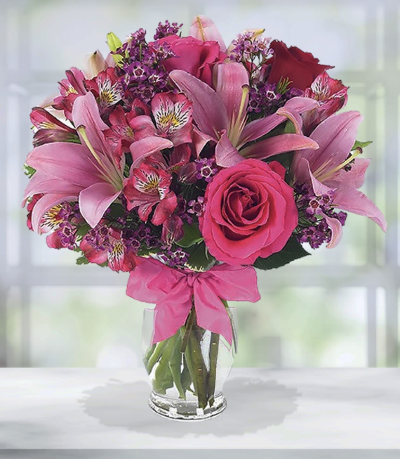 Pink and purple bouquet of lilies, roses, and alstroemeria in a glass vase
