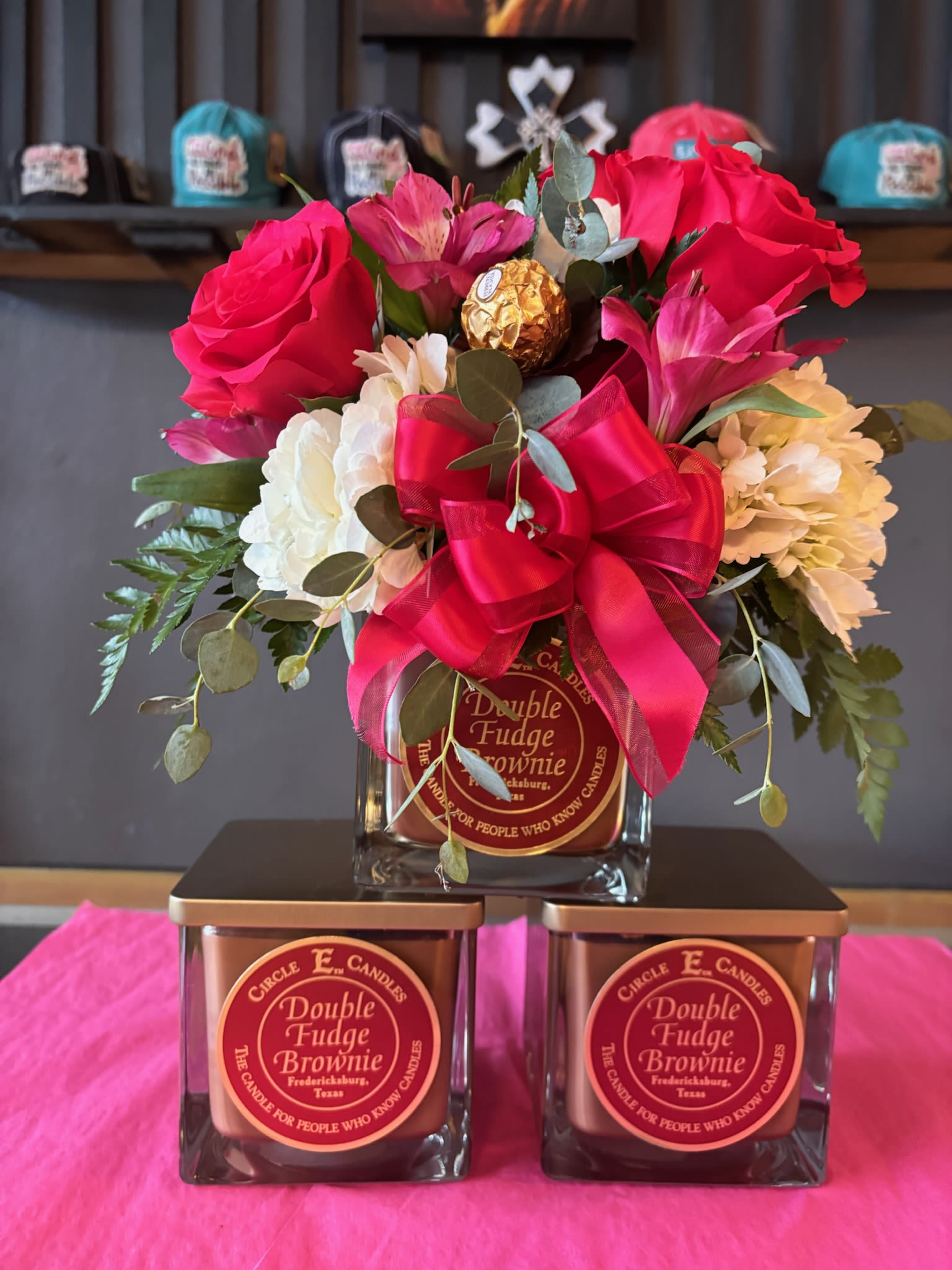 Bouquet of pink roses and mixed blooms with a red ribbon, arranged over candles