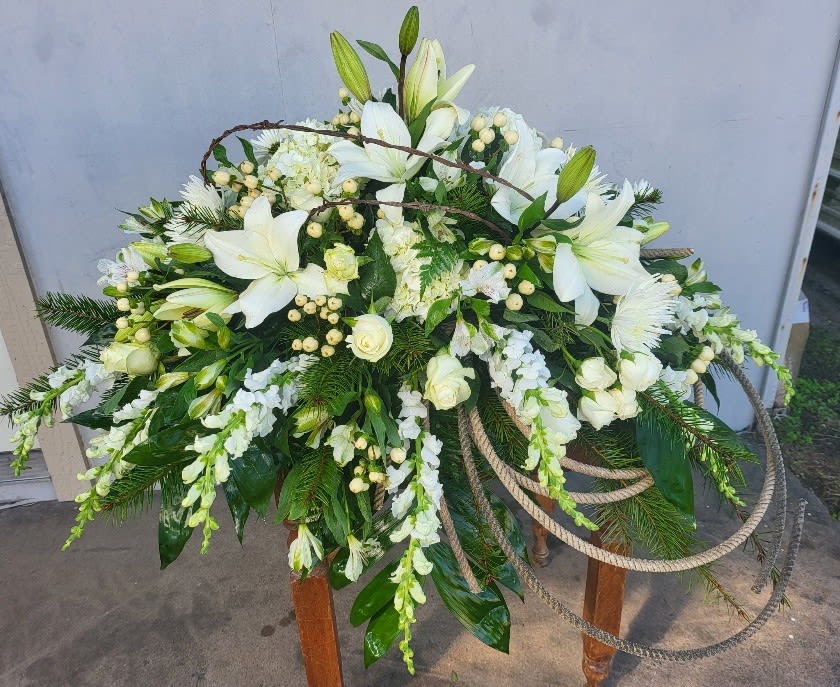 Large white floral spray with lilies and roses on a stand