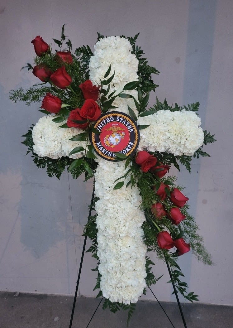 Cross-shaped floral tribute with white blooms and red roses on an easel