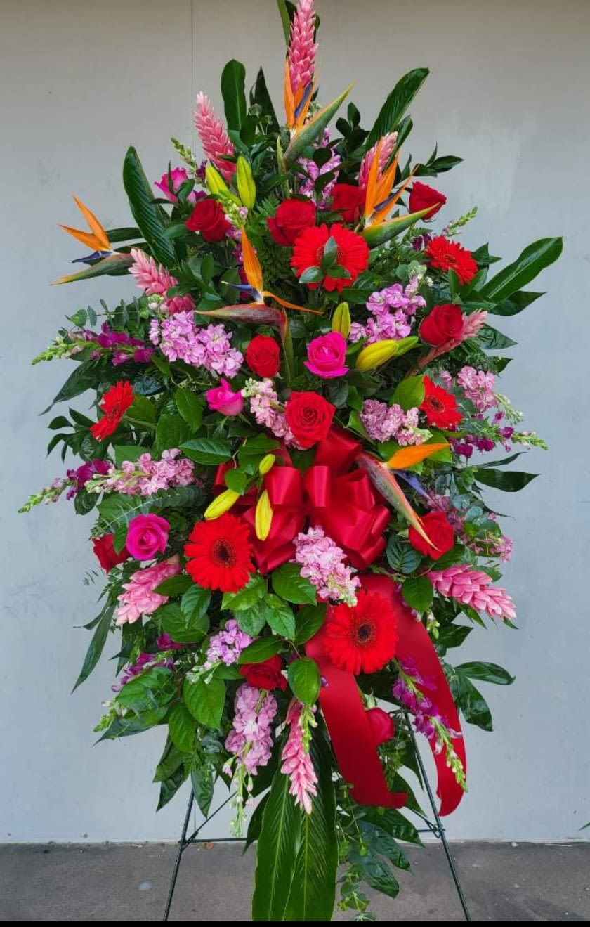 Tall standing floral spray with red roses, gerberas, and tropical blooms
