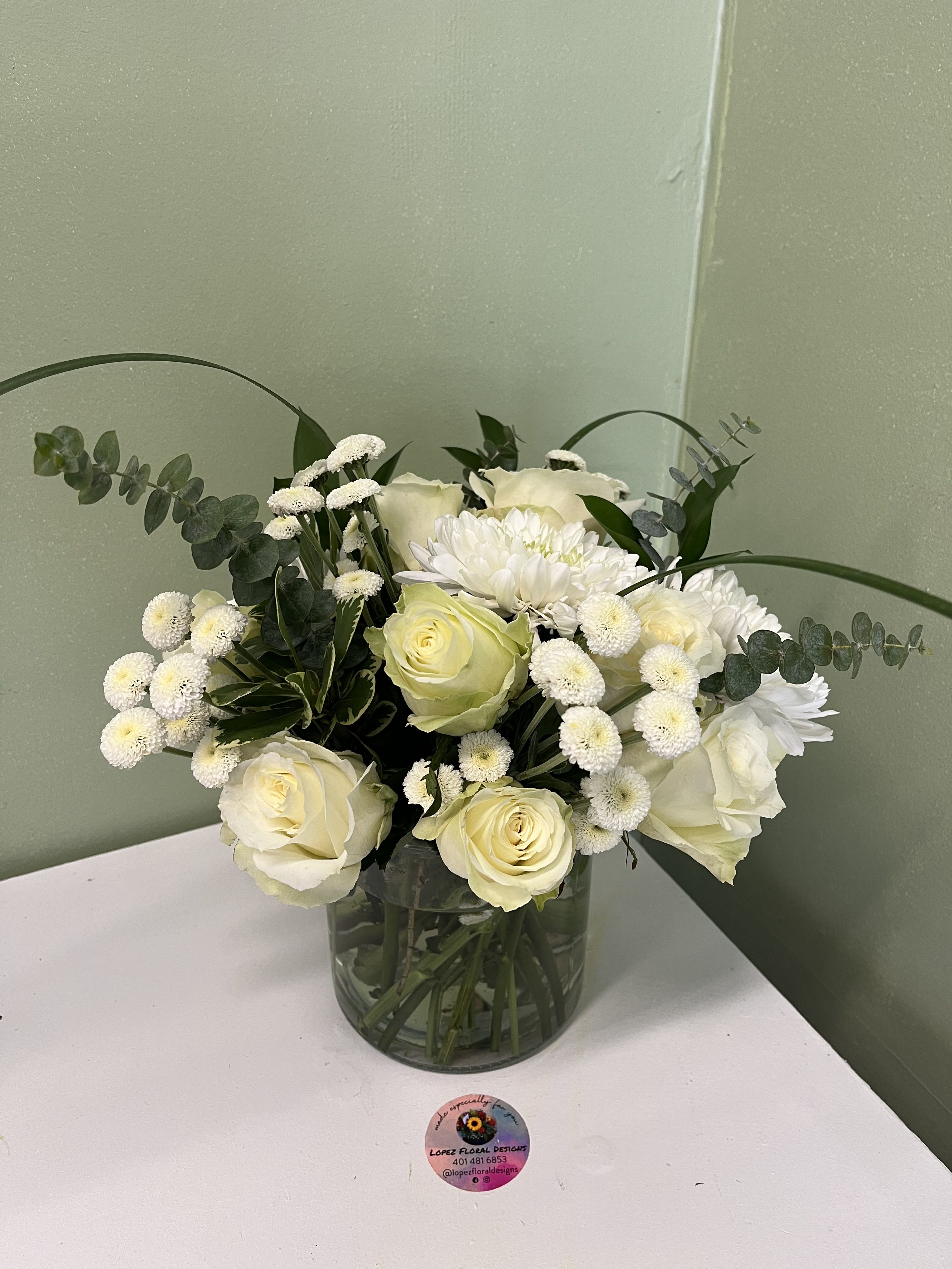 White roses and chrysanthemums in a glass vase with eucalyptus