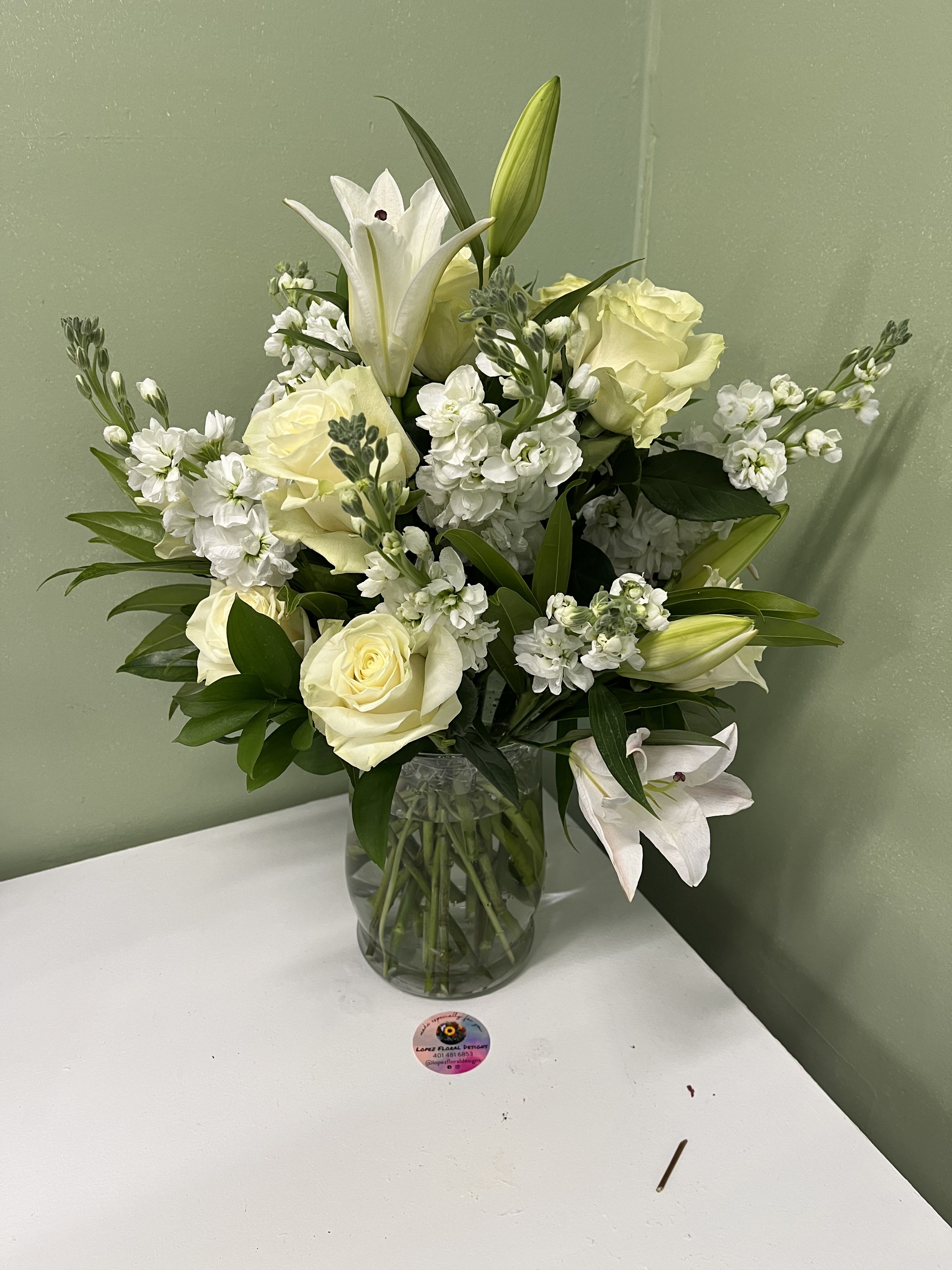 White lilies and roses arranged in a glass vase
