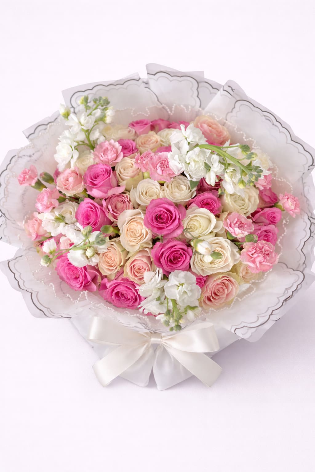 Bouquet of pink and cream roses with white flowers wrapped in white paper