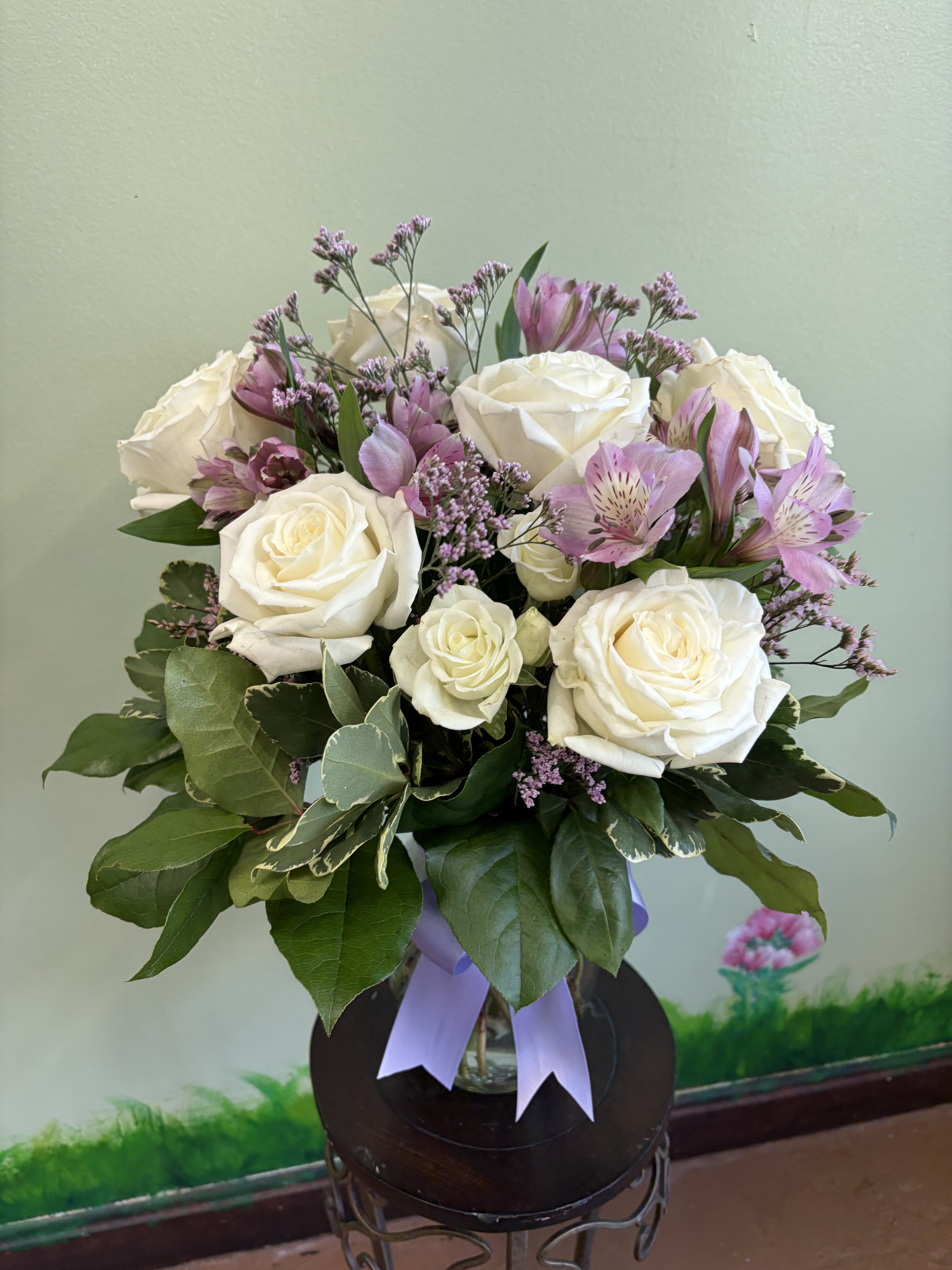 White rose and lavender alstroemeria arrangement in a clear vase with a lavender ribbon