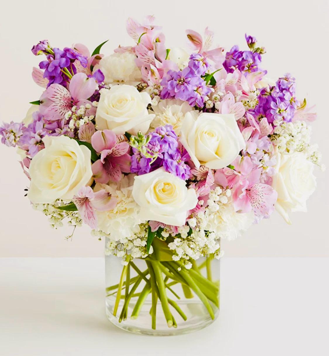 Pink and purple bouquet with white roses in a clear glass vase