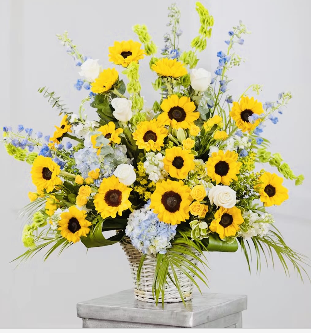 Basket arrangement with yellow sunflowers, white roses, and blue flowers