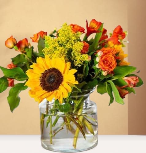 Sunflower and orange rose bouquet in a clear glass vase