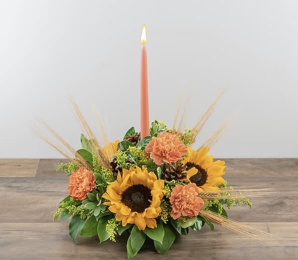 Sunflower and carnation centerpiece with a tall coral taper candle