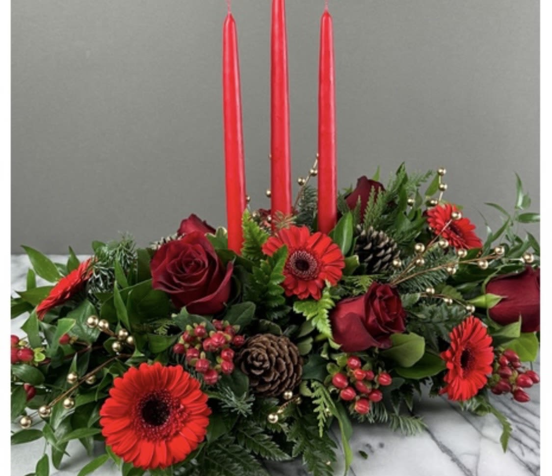Low floral centerpiece with red roses, red gerbera daisies, and tall red candles