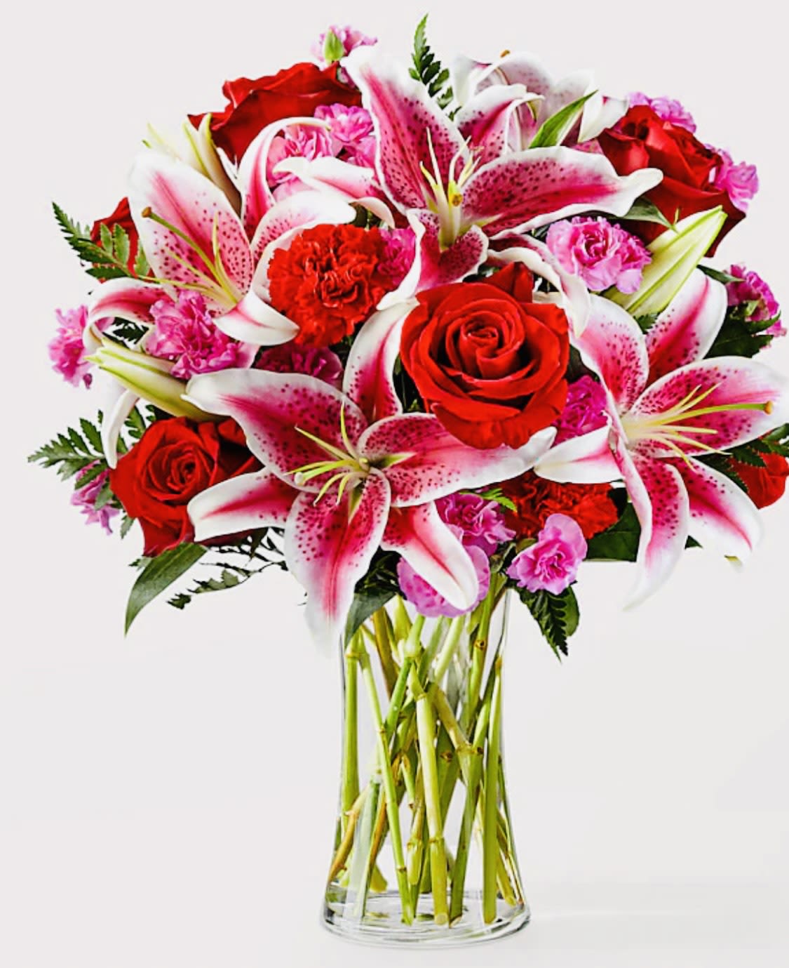 Bouquet of red roses and pink lilies in a clear glass vase