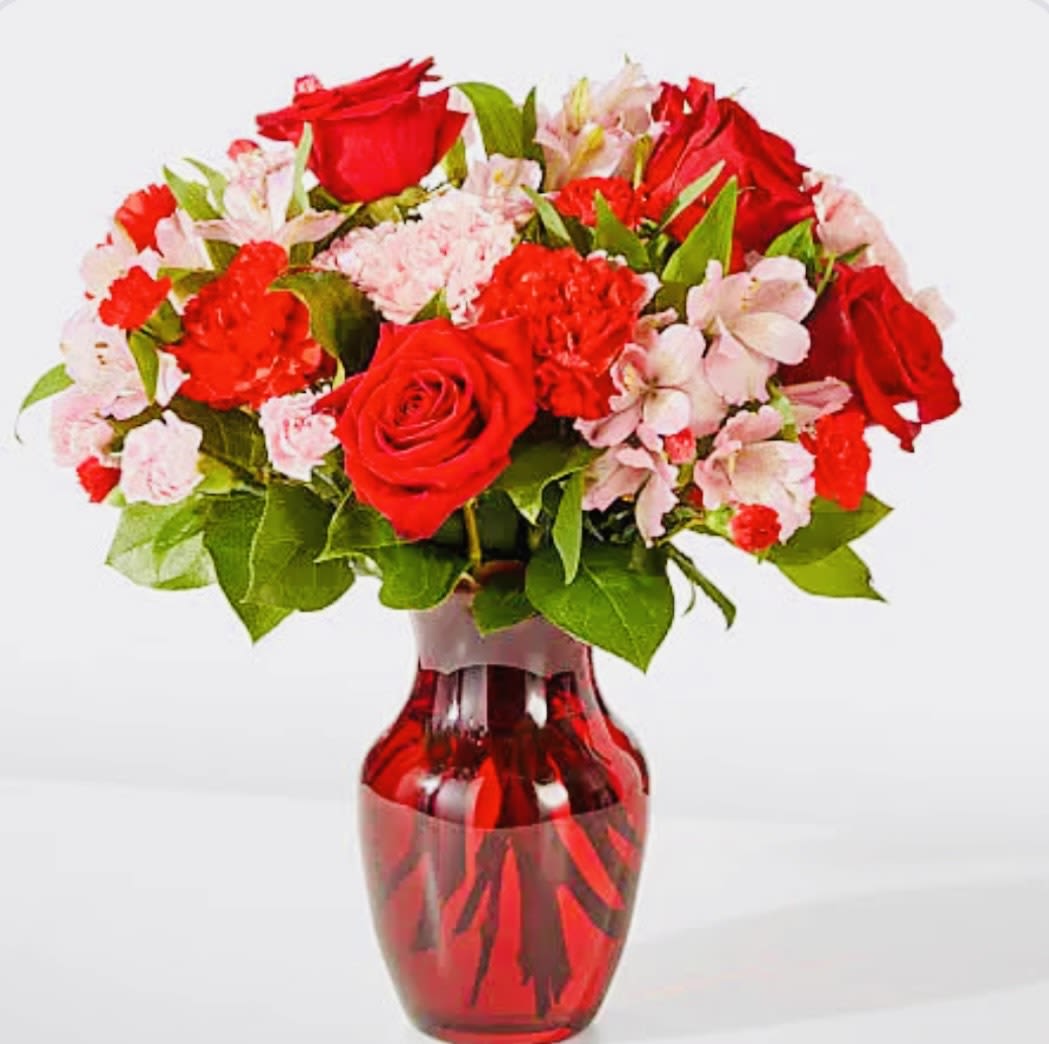 Red roses and pink flowers in a red glass vase