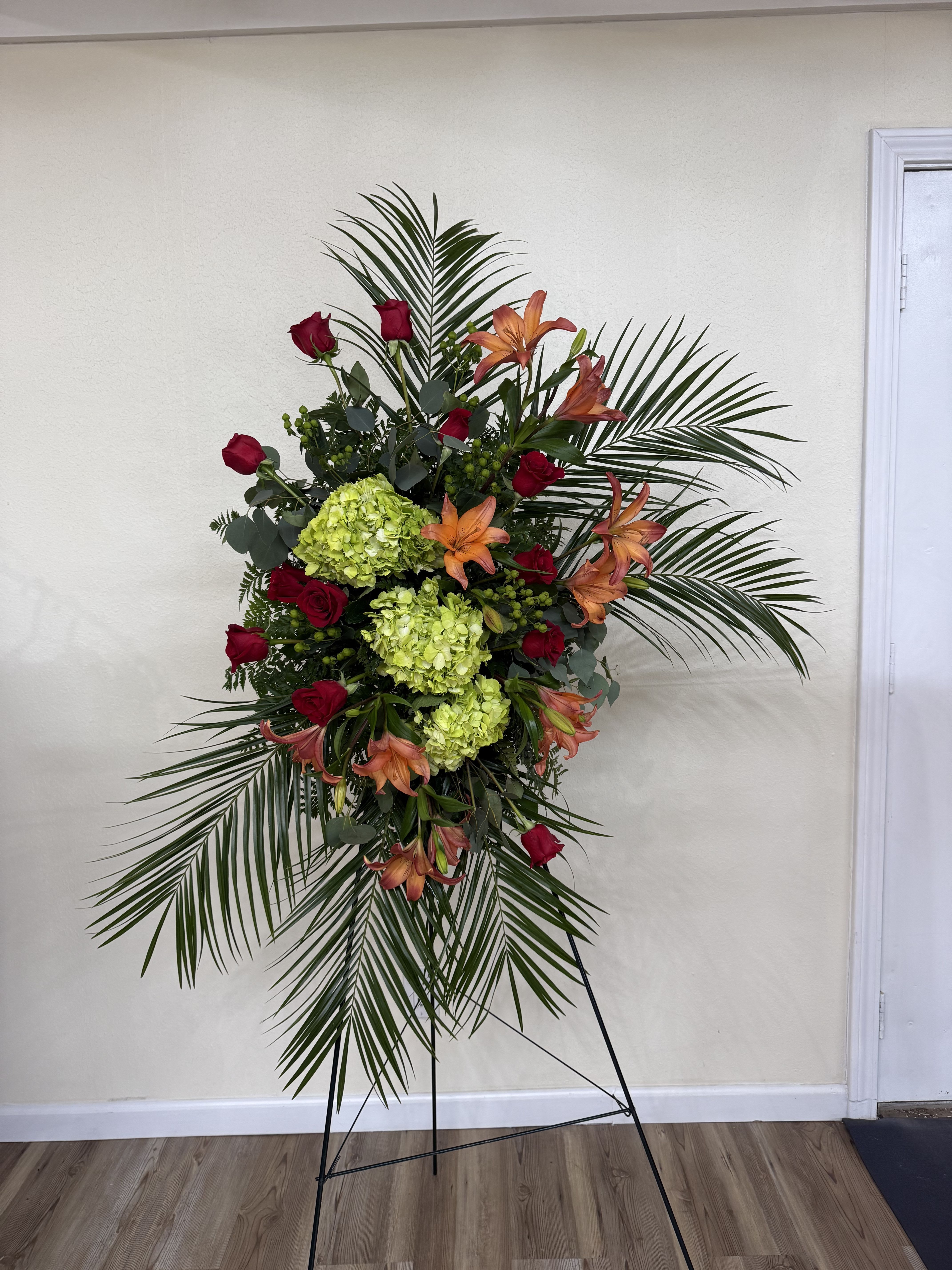 Standing floral spray with red roses, orange lilies, and green hydrangeas