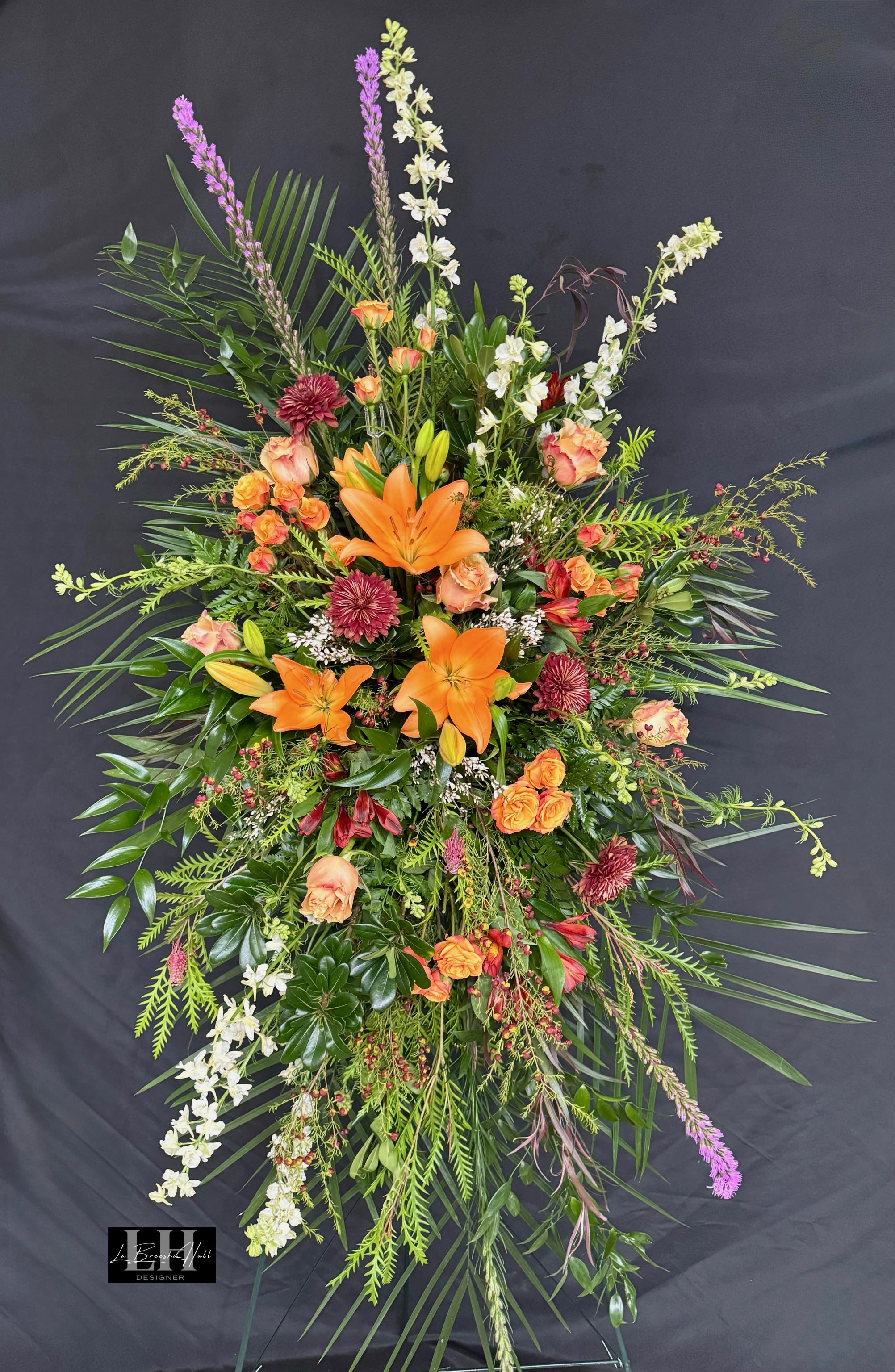Tall floral spray with orange lilies, roses, and white blossoms