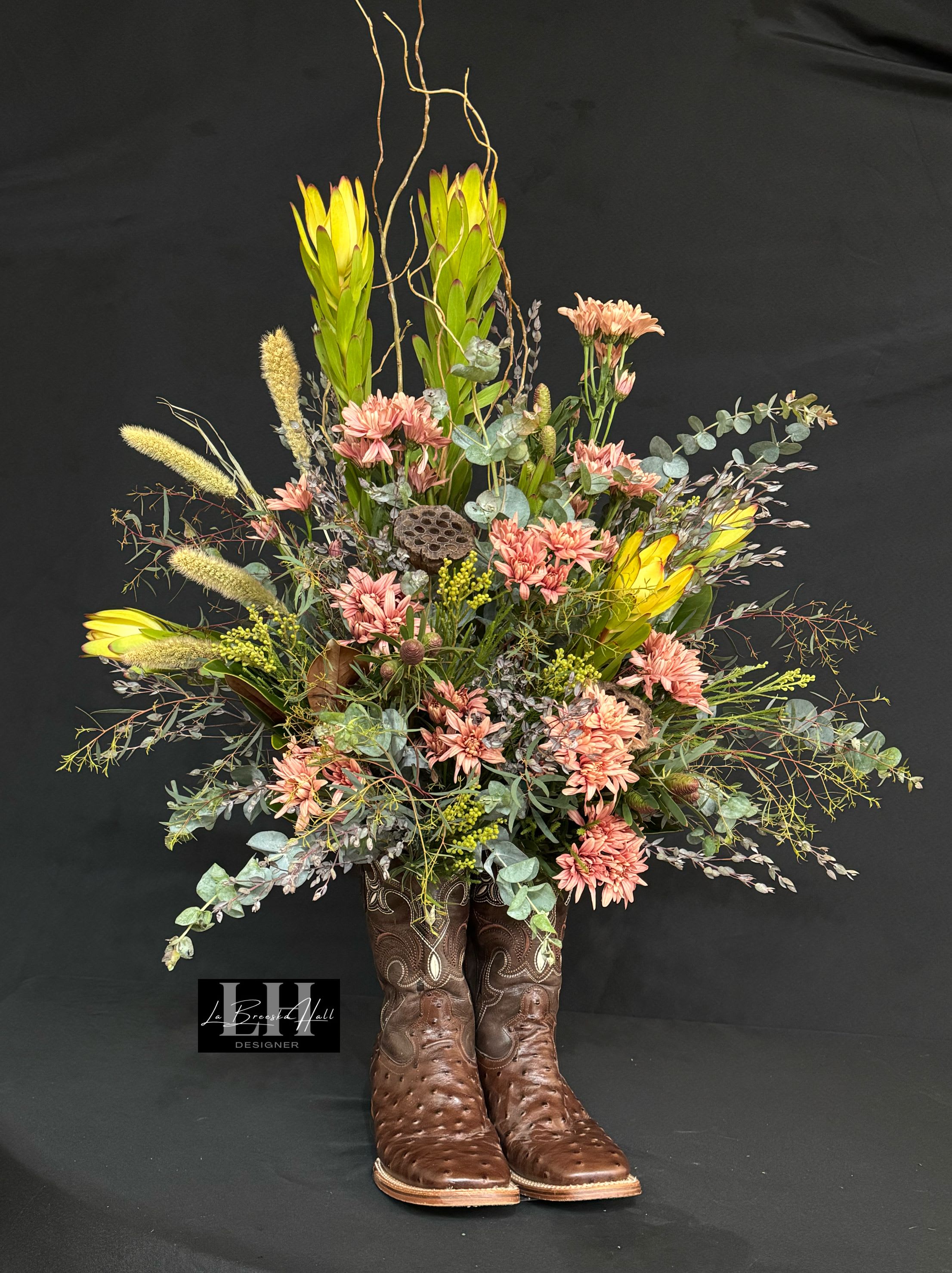 Tall floral arrangement in brown cowboy boots with pink and yellow blooms