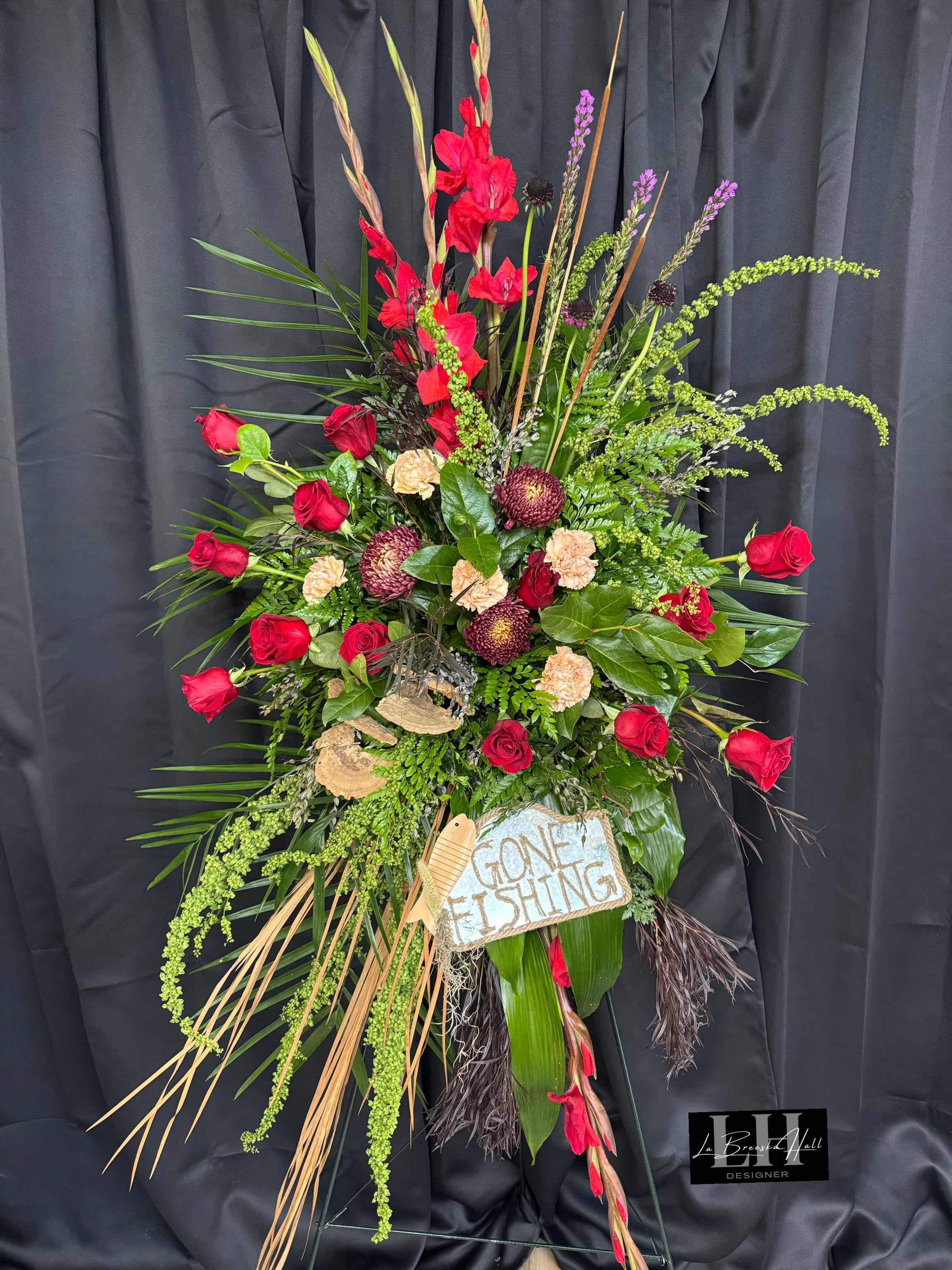 Tall floral standing spray with red roses and mixed greenery