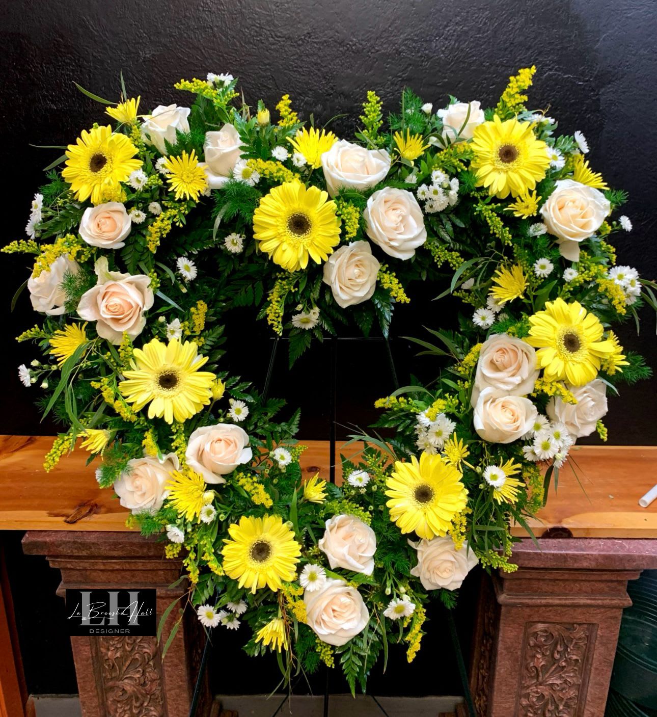 Heart-shaped floral arrangement with yellow gerbera daisies and cream roses