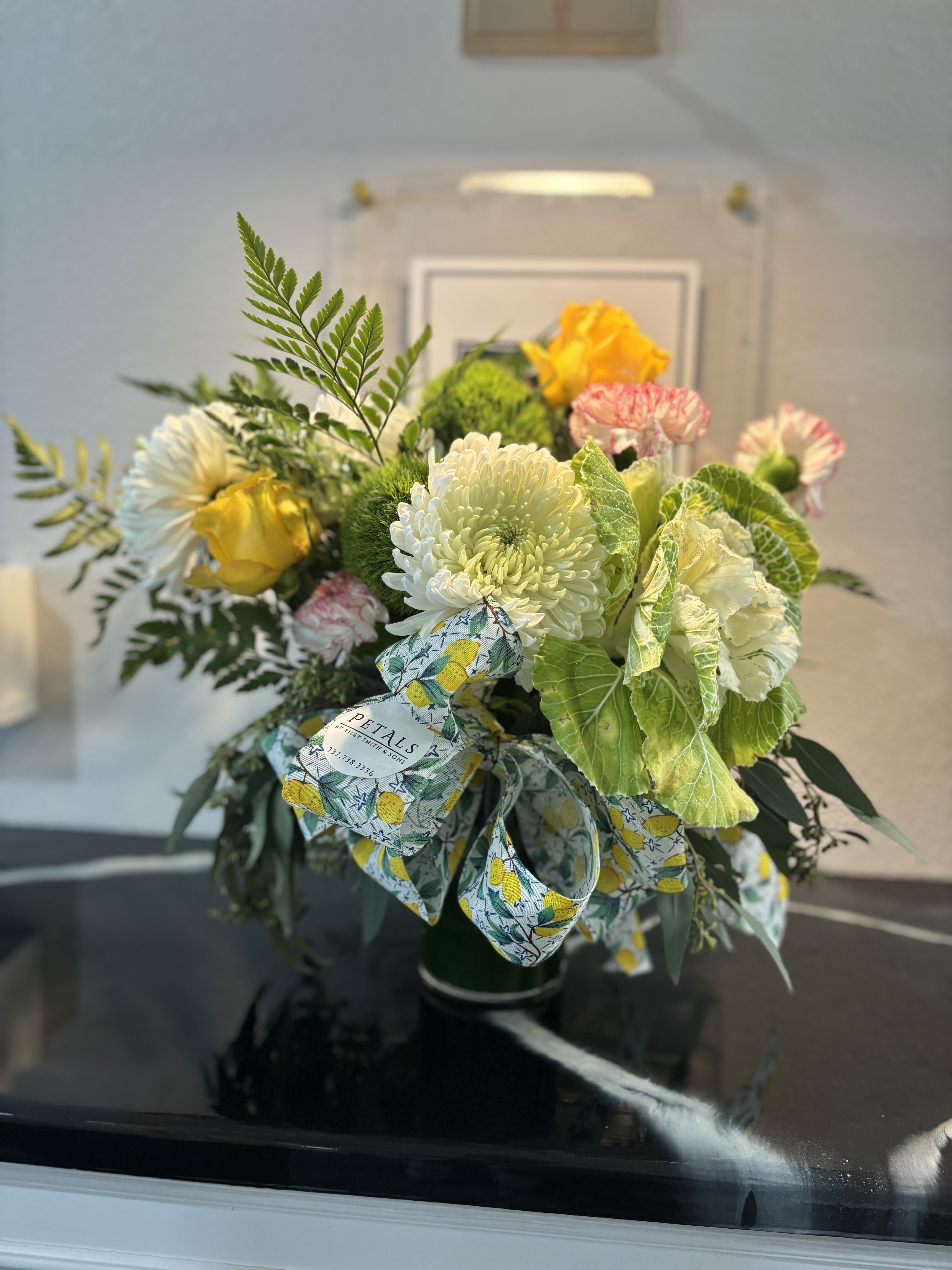 Bouquet of white and yellow flowers with a lemon-patterned ribbon in a vase