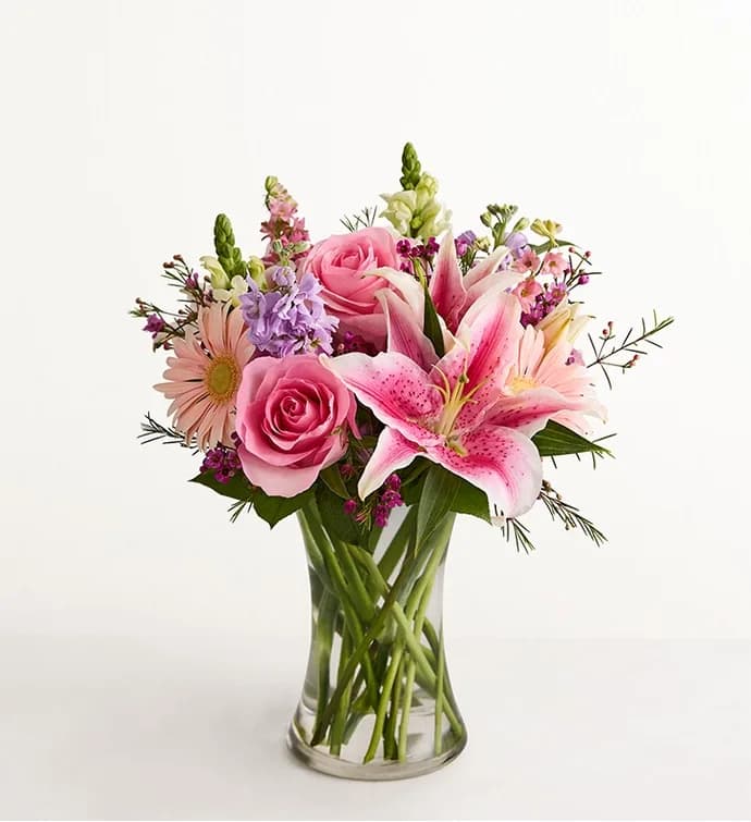 Pink roses and lilies arranged in a clear glass vase