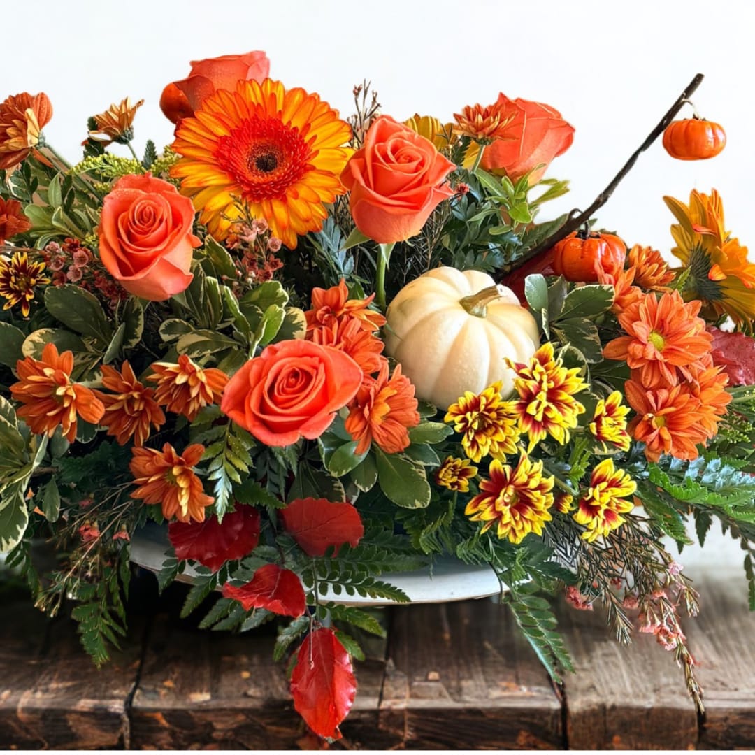 Autumn floral arrangement with orange roses, gerbera daisies, and small pumpkins