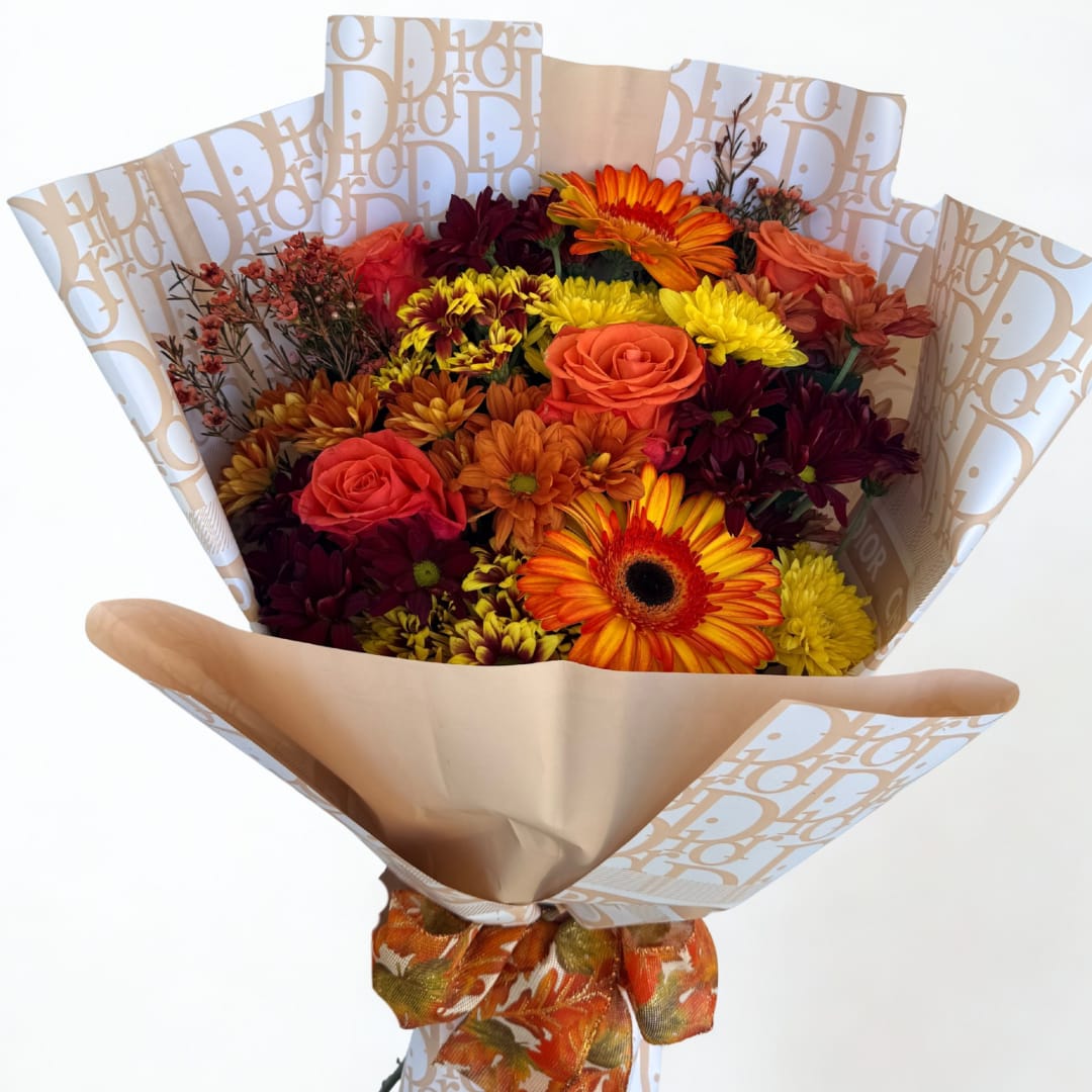 Bouquet of orange, yellow, and burgundy flowers wrapped in patterned paper
