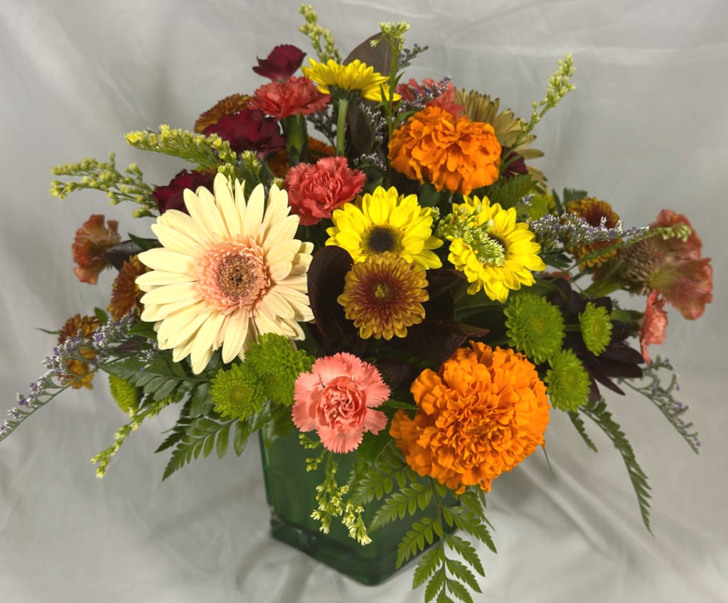 Mixed bouquet of gerbera daisies and carnations in a green glass vase