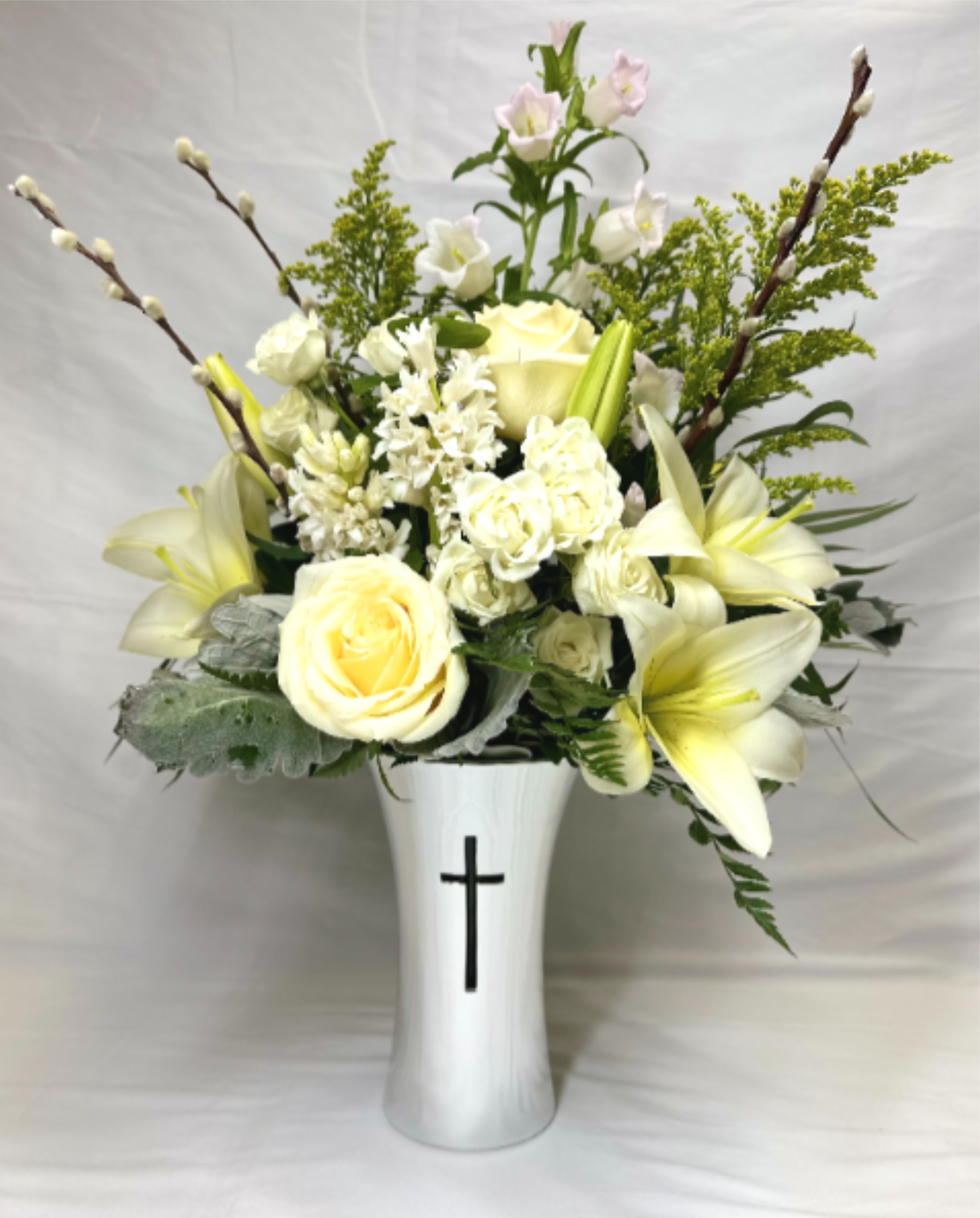 White and pale yellow lilies and roses in a white vase with a black cross motif
