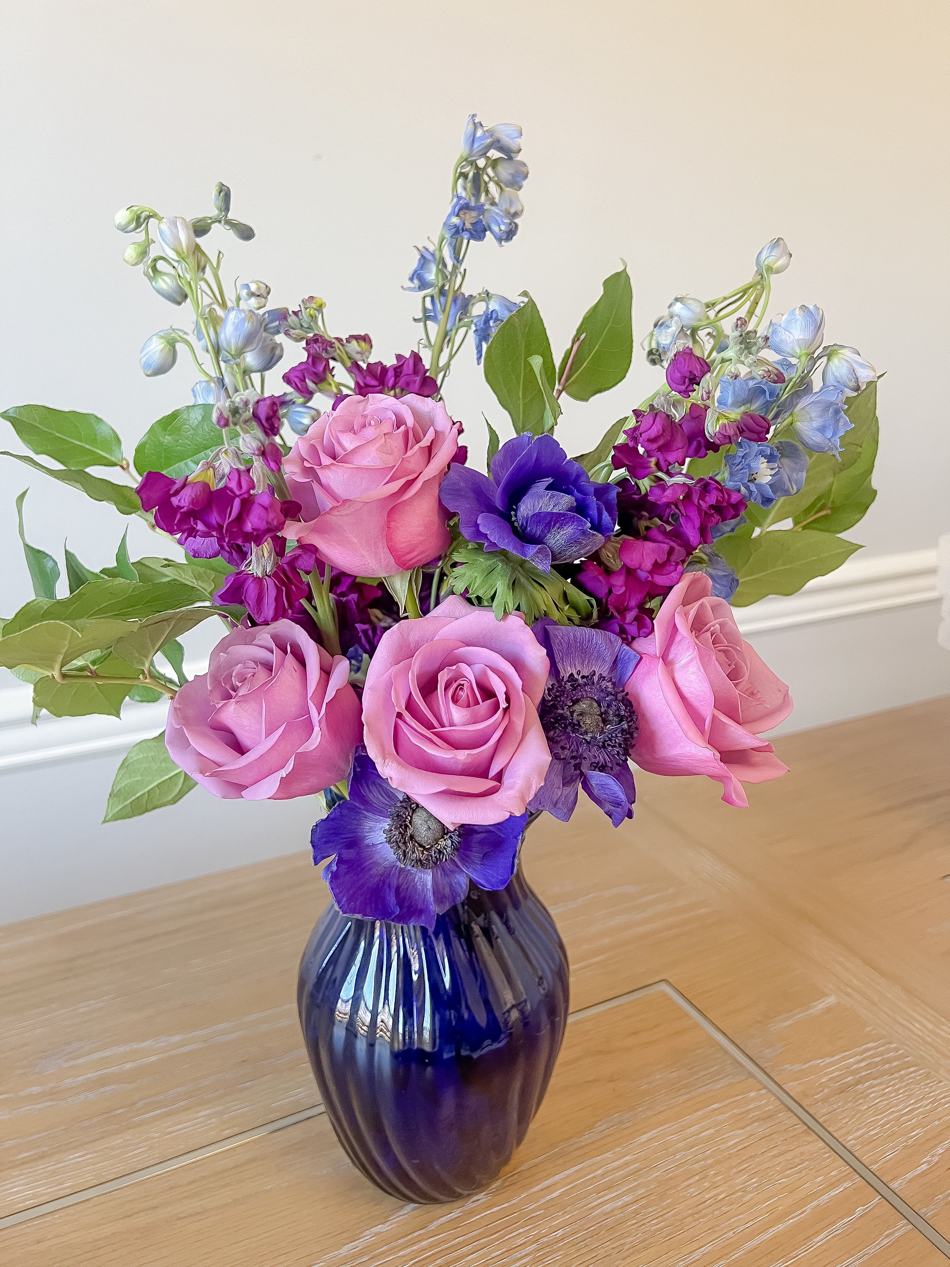 Pink and purple flower bouquet in a dark glass vase