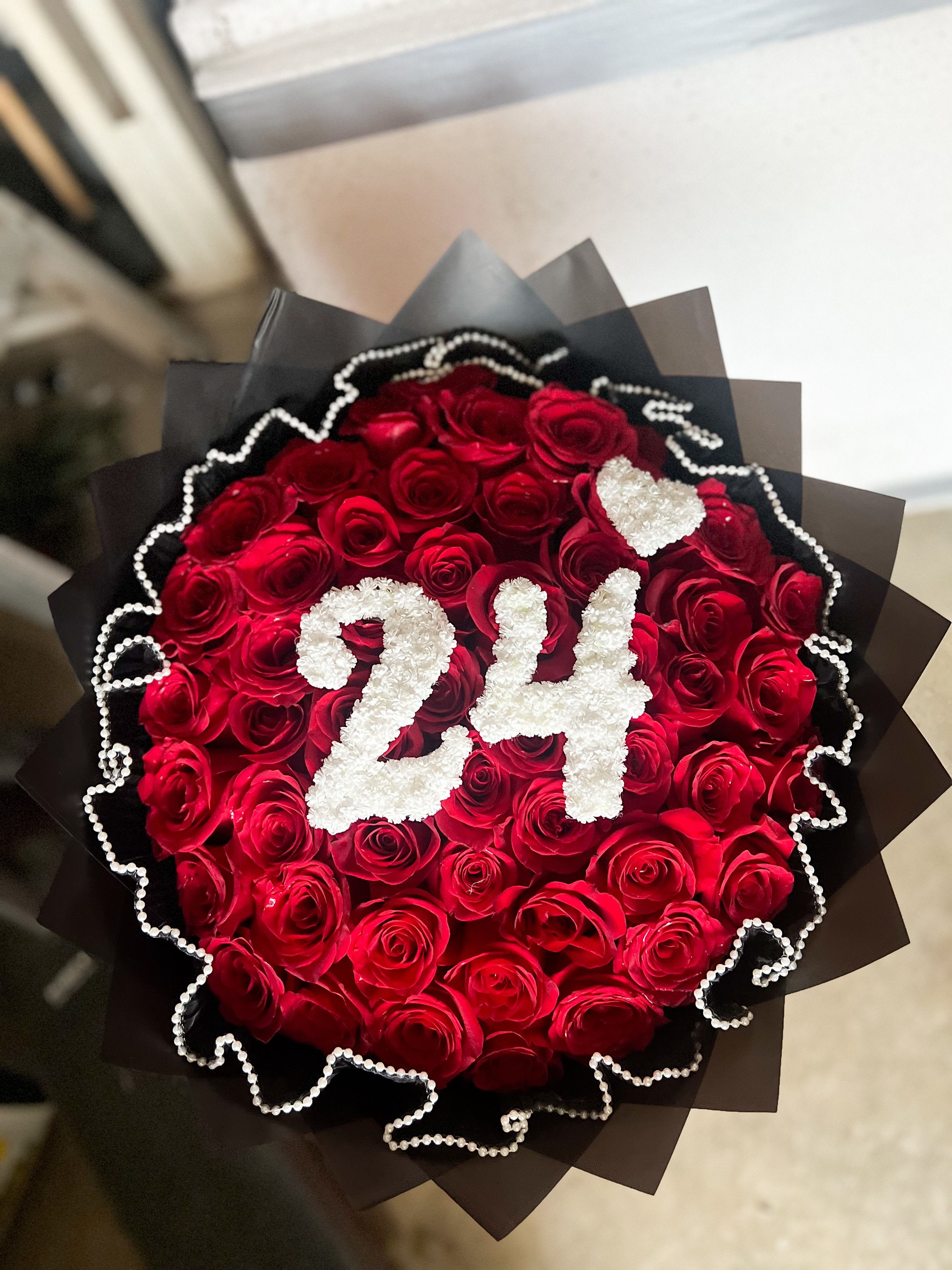 Bouquet of red roses with white "24" decoration and black wrap