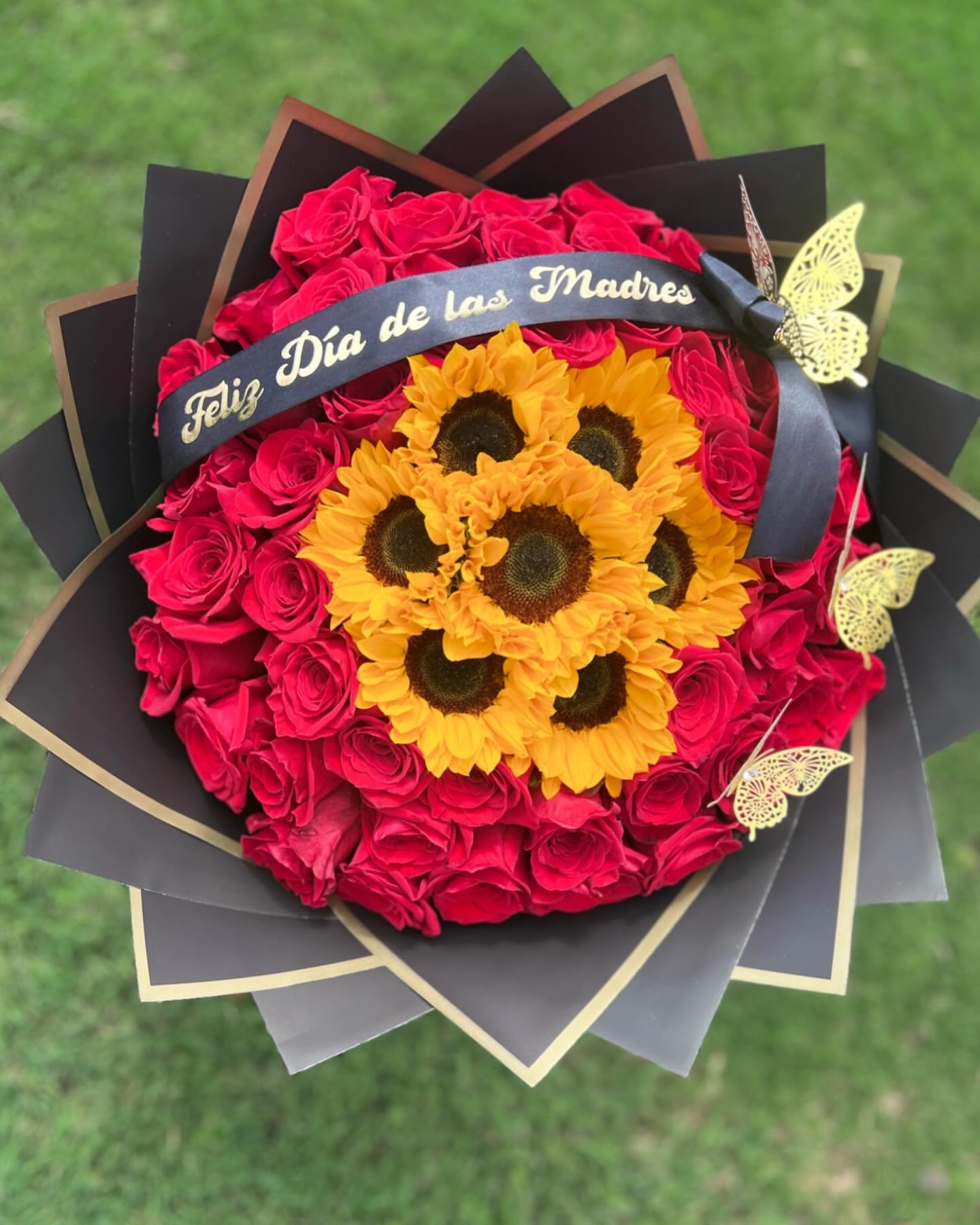 Bouquet of red roses and yellow sunflowers with a Mother's Day ribbon