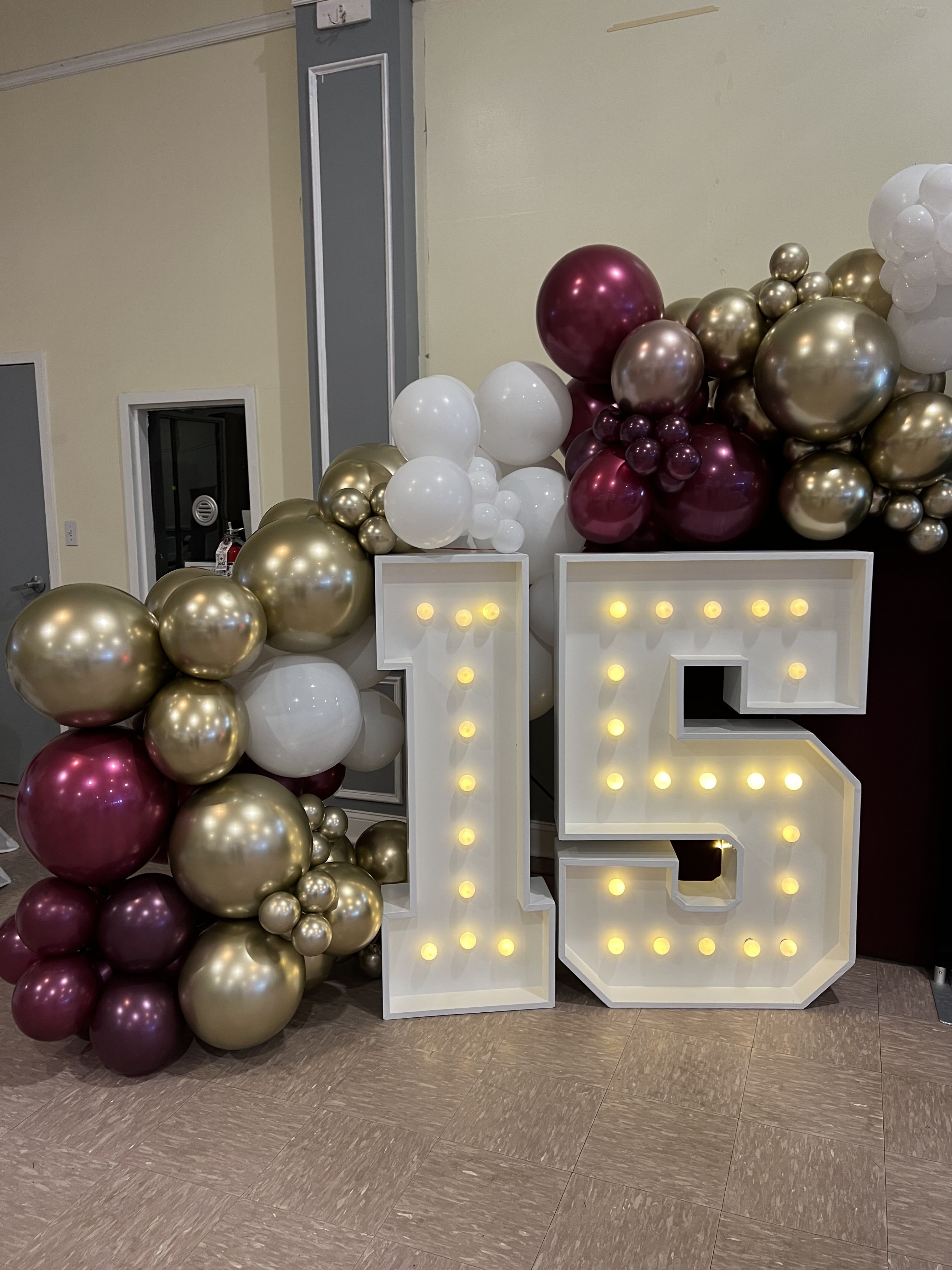 Balloon display with large lit numbers 1 and 5 in front of metallic balloons.