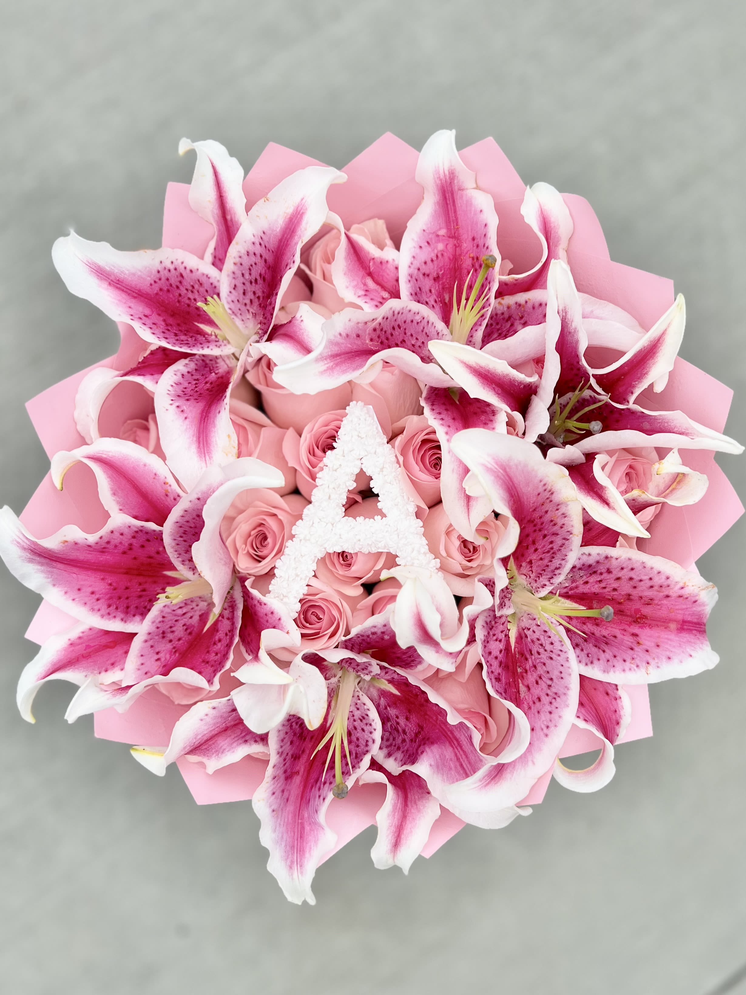 Pink lilies and roses arranged in a bouquet with pink wrapping