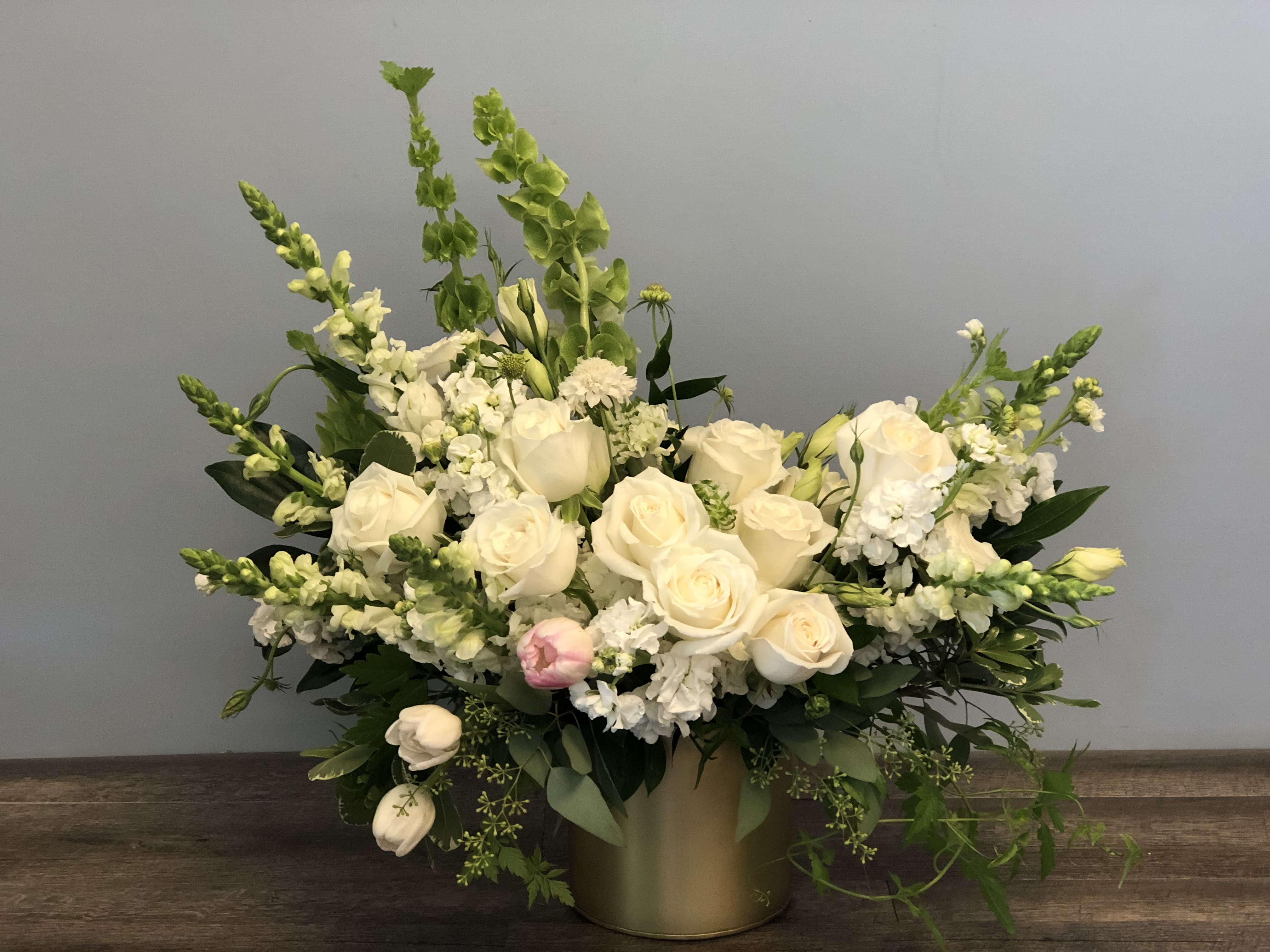 White rose arrangement with tall green spikes in a gold vase