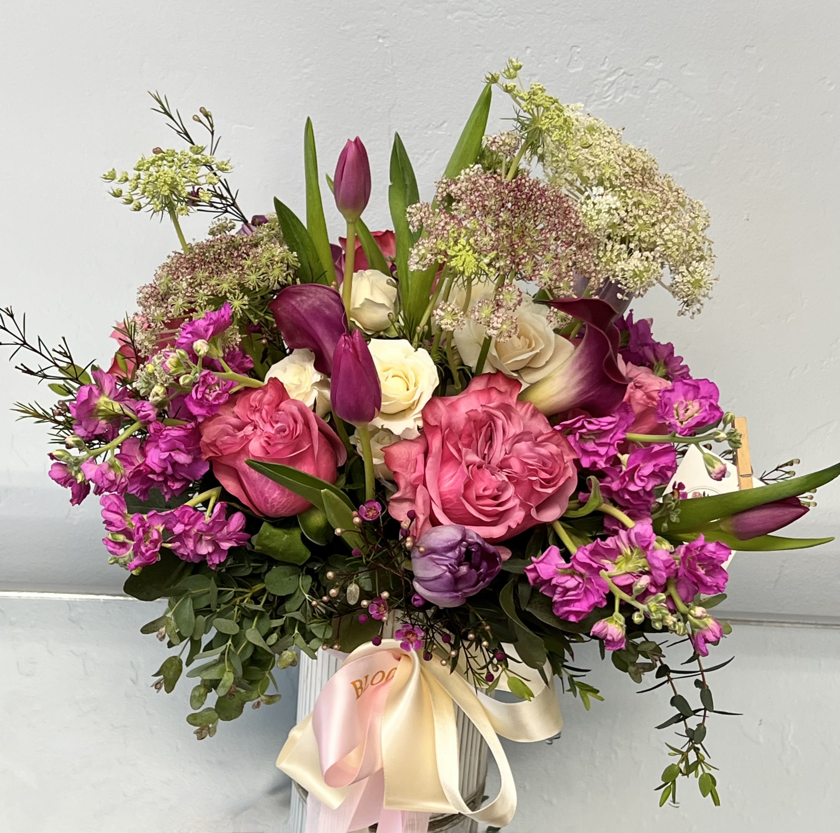 Bouquet of pink roses, purple tulips, and white calla lilies in a vase