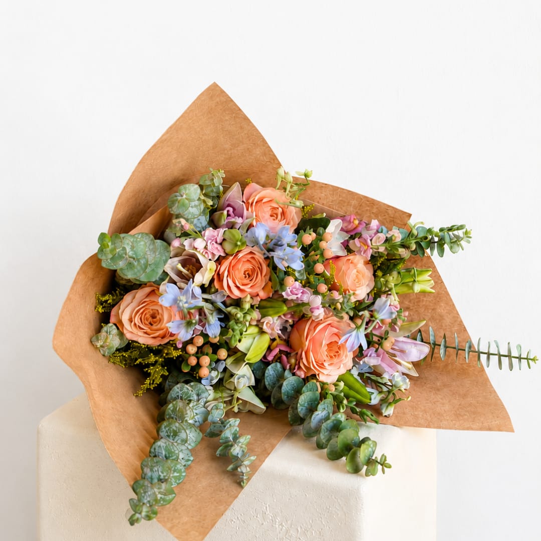 Peach roses and pastel flowers wrapped in brown paper